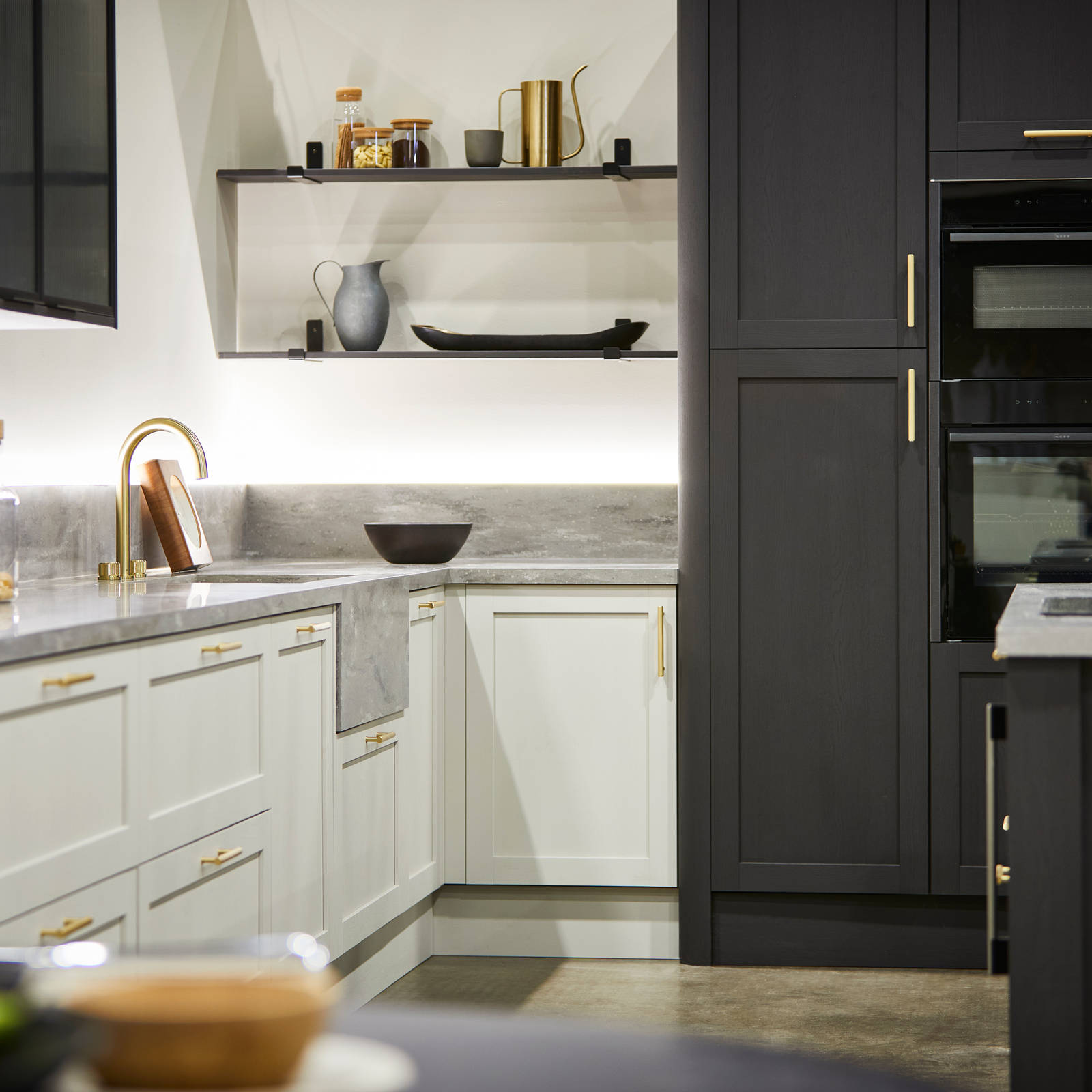 The Ambleside kitchen in Limestone and Graphite, paired with brass bar handles, a grey worktop and modern brass tap.