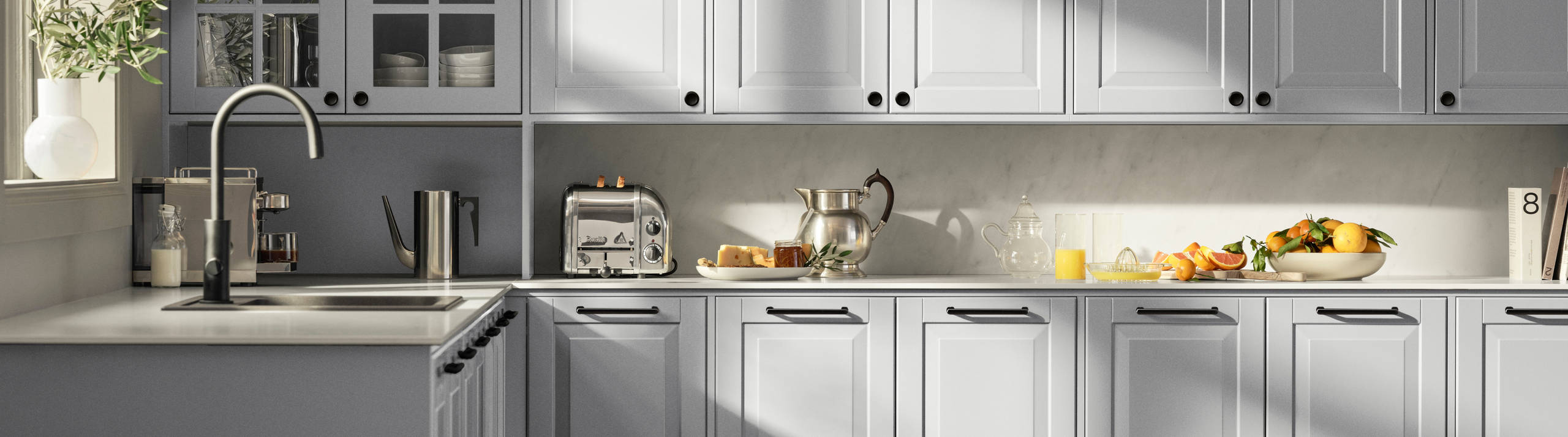 Lys grå landkøkken Nordic Sky fra INVITA med fyldningslåger, sort håndtag, vitrineskab med sprosselåger og hvid marmor laminatbordplade