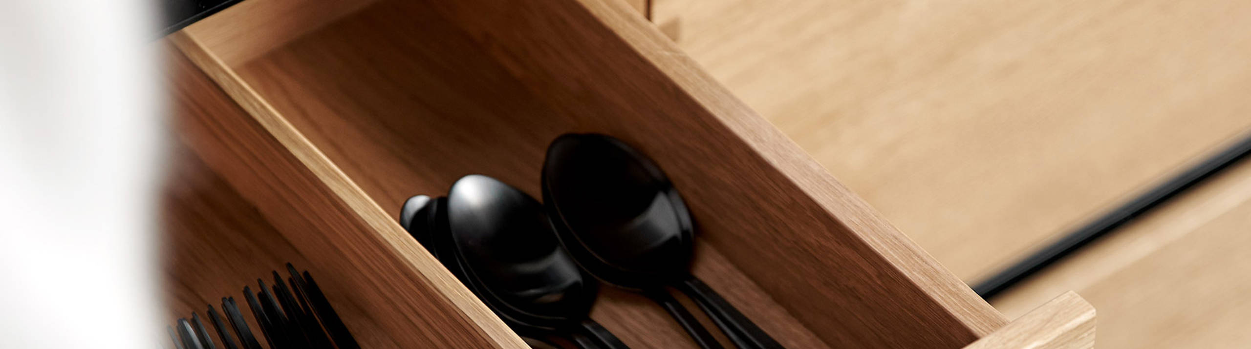 Nærbild av køkken Glød fra INVITA, åben bestikskuffe i massivt egetræ med fingertappede samlinger  og sort granit bordplade