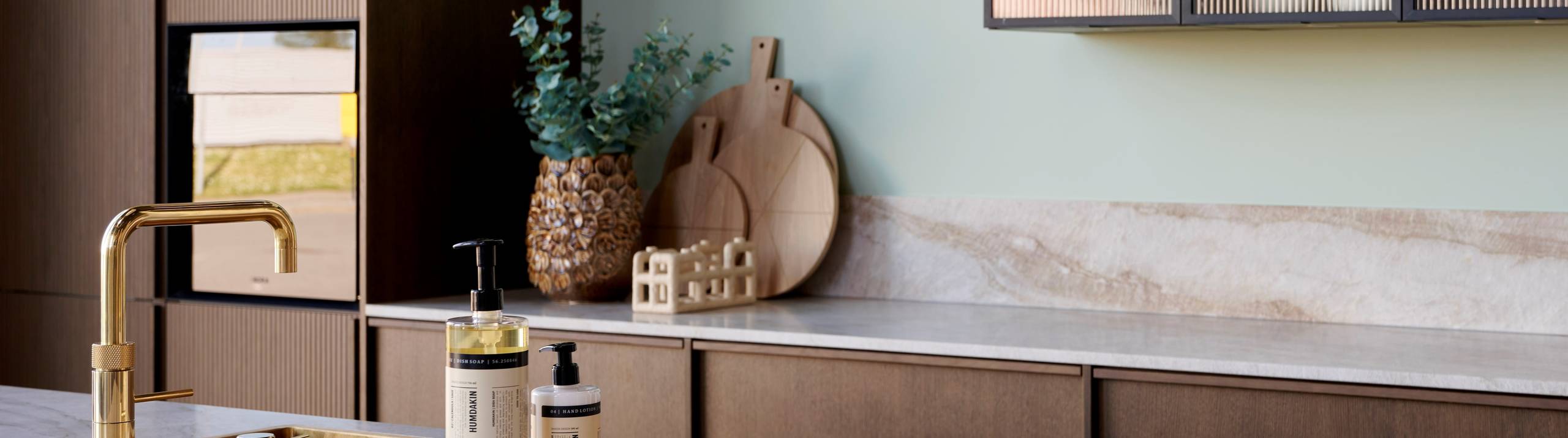 Mørk eg køkken Forever Oak med køkkenø fra INVITA med marmor bordplade og Vitrineskab med rifled glas og sort aluminiumsramme.