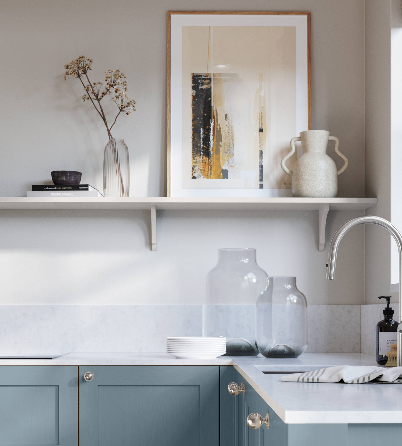 Wardley Portland Blue kitchen cabinetry with steel knobs, steel tap, white marbled worktop and matching backsplas, an open shelf on the wall above cabinets with ceramics and a vase of flowers.