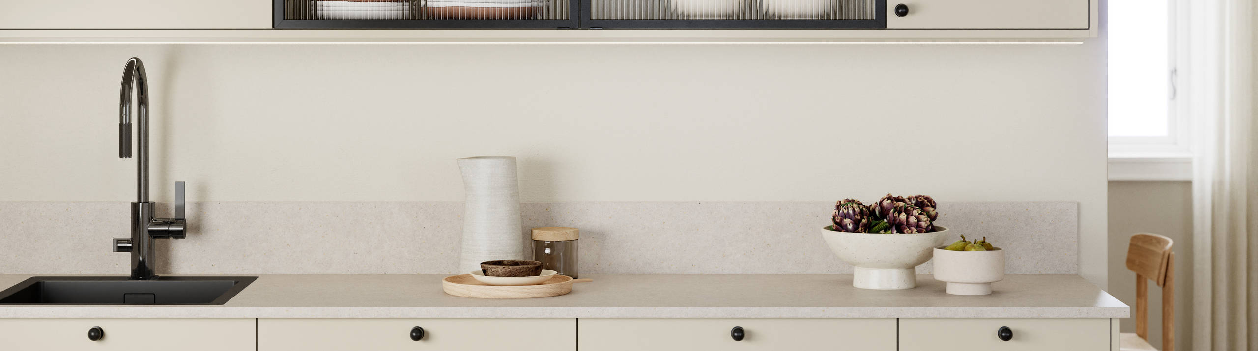 Beige melaminkjøkken Vidde Korn med sorte håndtag, sort kran, og vitrinedør med sort aluminiumsramme og rillede glass.