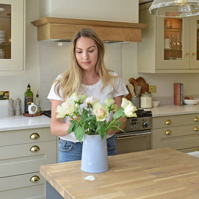 Magnet kitchen customer Leanne placing roses in a case on the kitchen island counter in her country cottage.