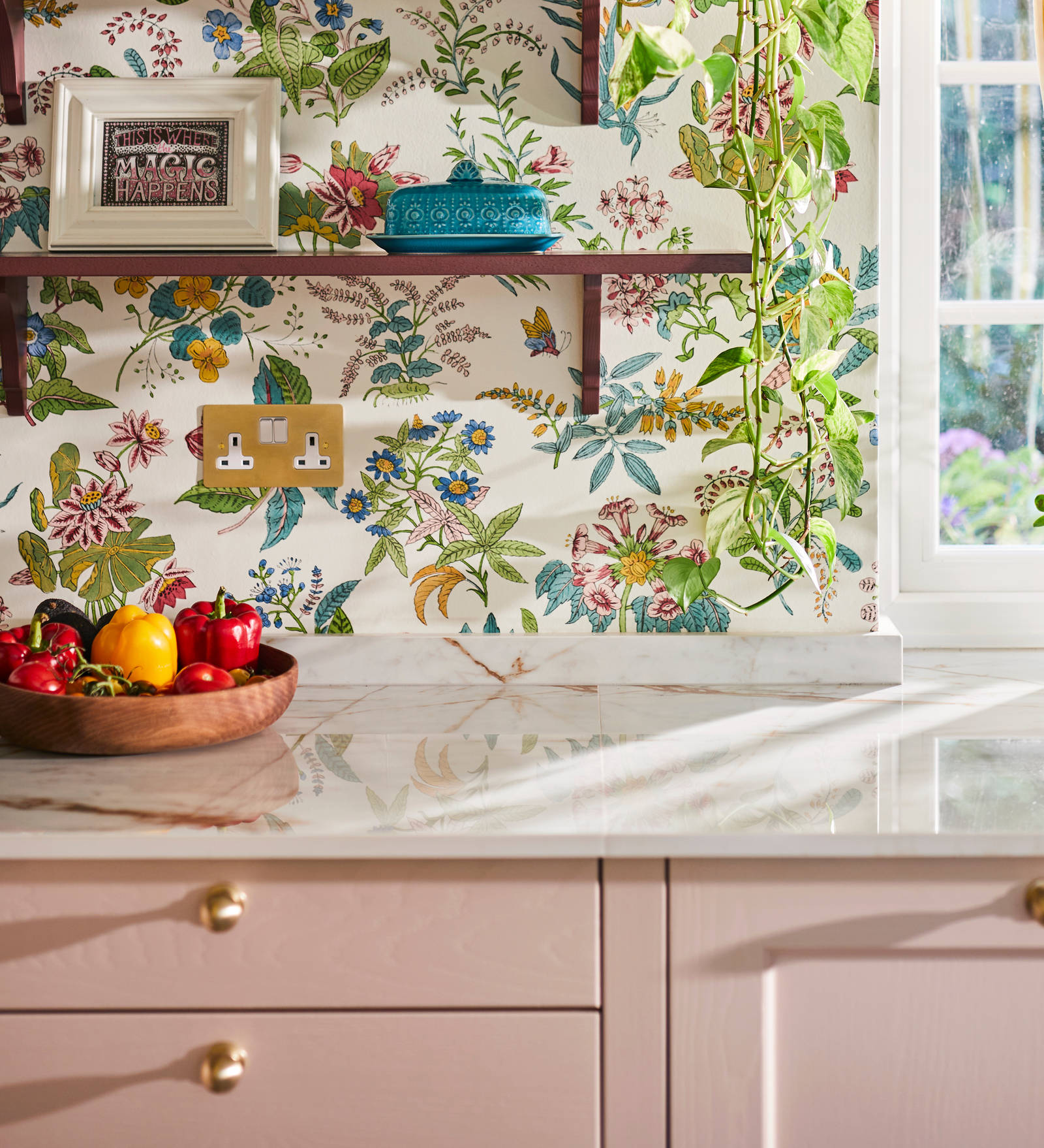 Colourful floral wallpaper, burgundy colour open shelves with colourful decorations over Ludlow Chalk blush cabinets.