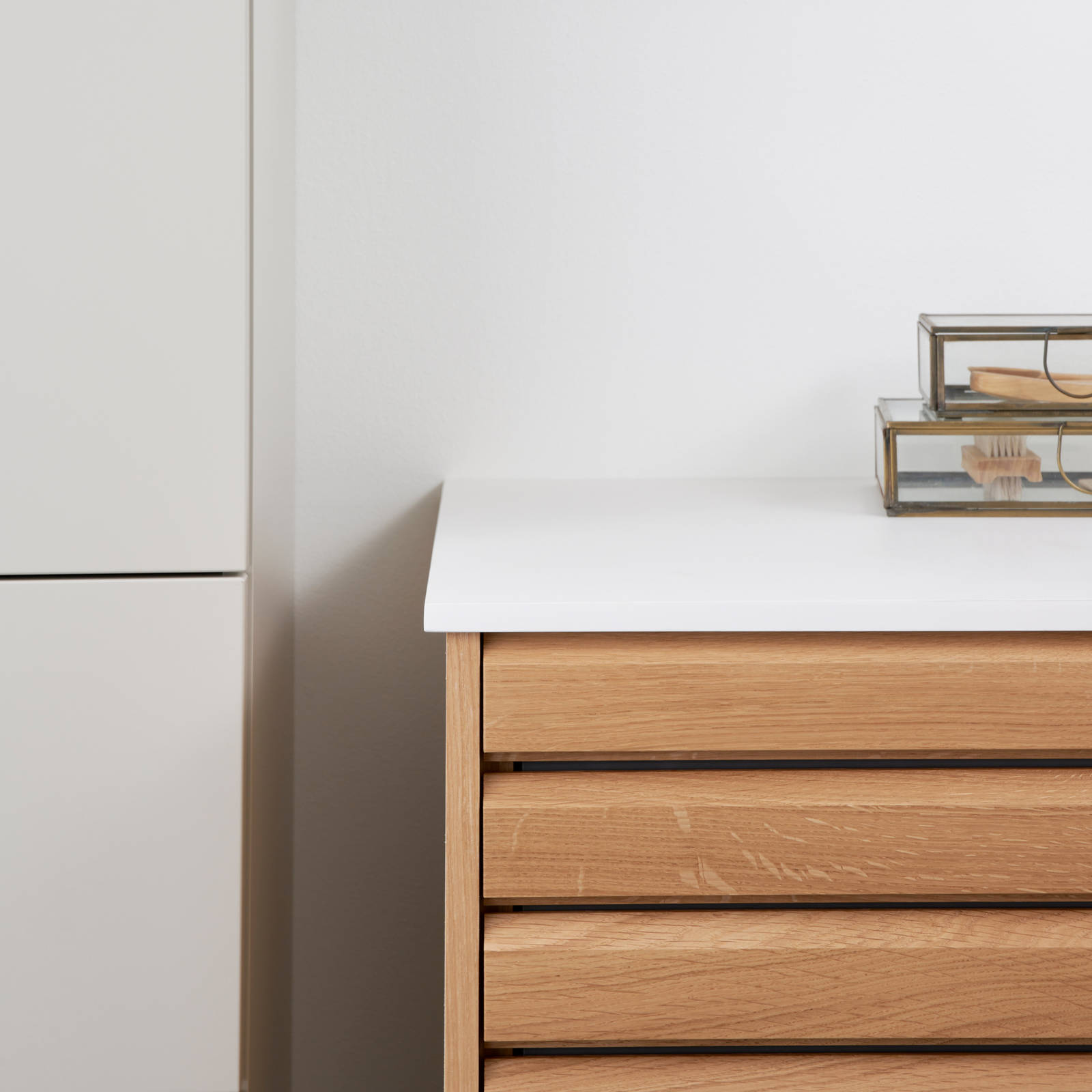 Nærbillede af hjørne i snedkerbadeværelse Ikon Finér eg natur fra INVITA med håndplukkede, massive egetræslameller med hvid vask