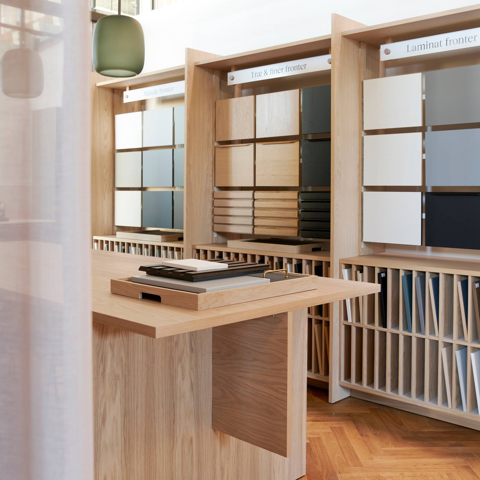 Væghylder med prøver af køkkenlåger i forskellige stilarter og farver i INVITAs butik