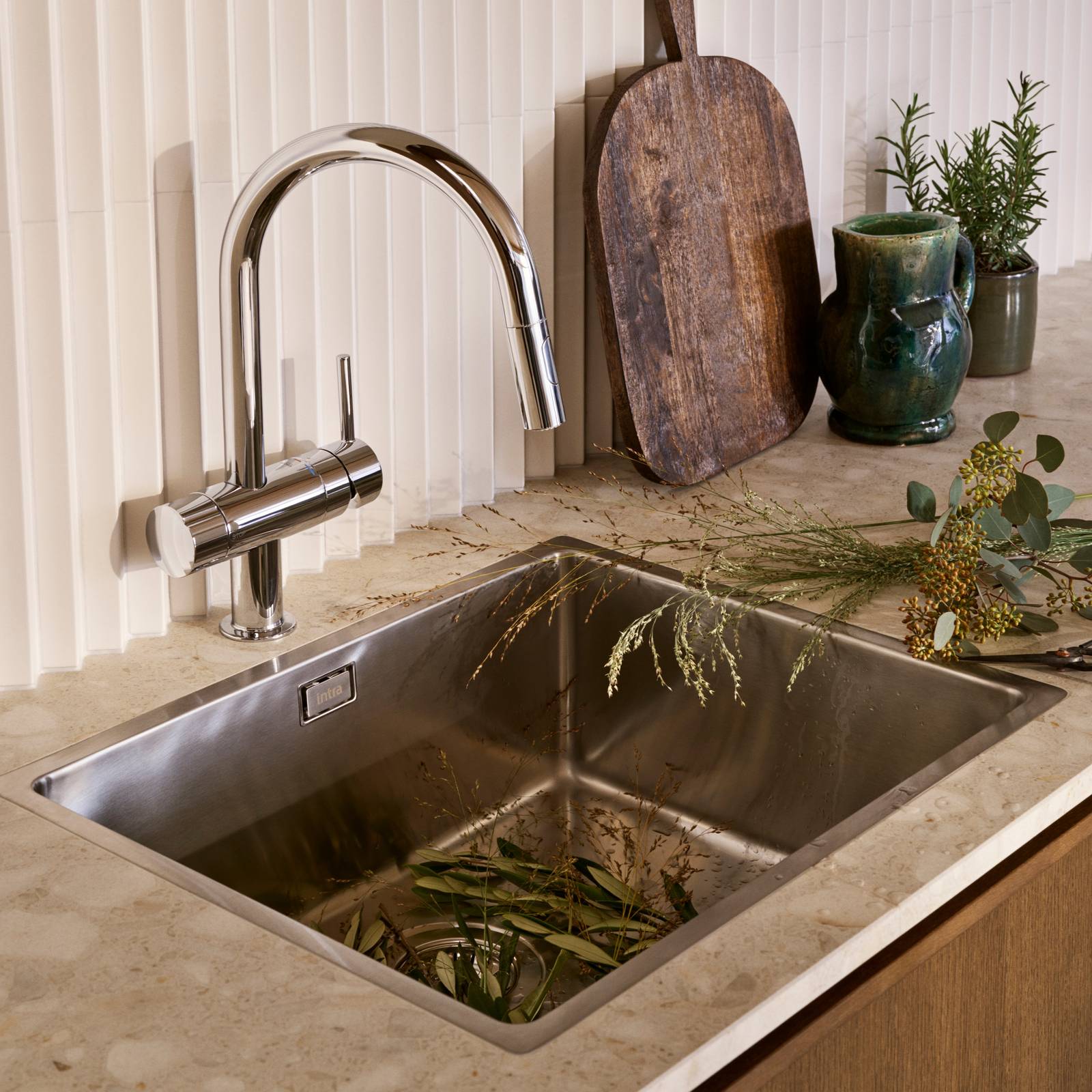 Nærbillede av rustfrit stål vask og armatur i mørk eg køkkenet Forever Oak fra INVITA med hvid fliser backsplash