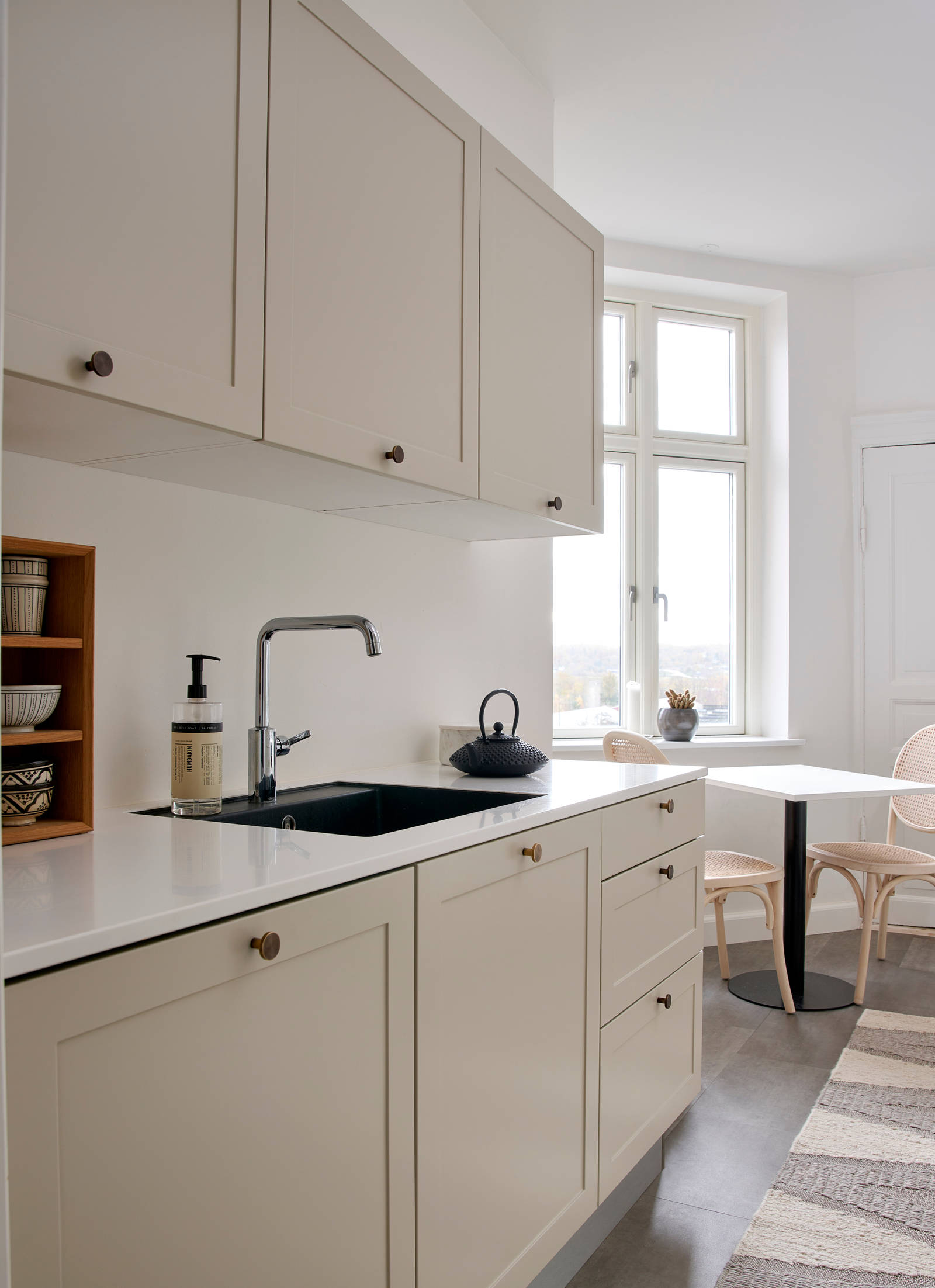 Beige retrokøkken Square Sand køkken fra INVITA med messing håndtag, hvid bordplade