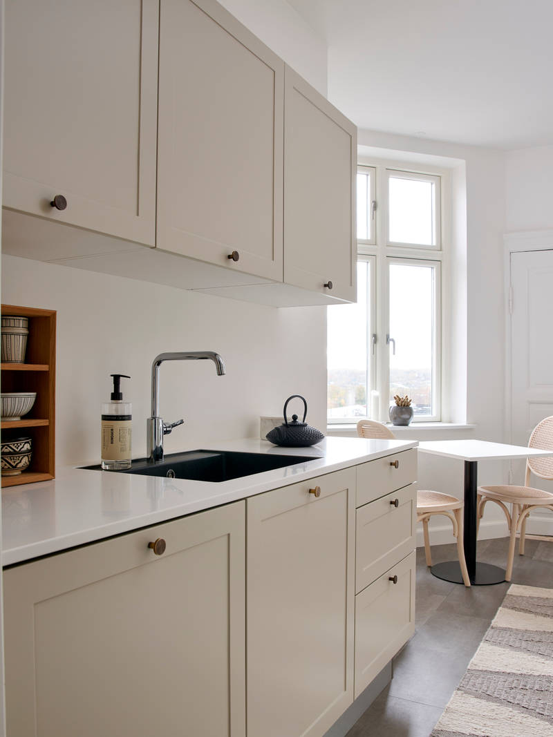 Beige retrokøkken Square Sand køkken fra INVITA med messing håndtag, hvid bordplade