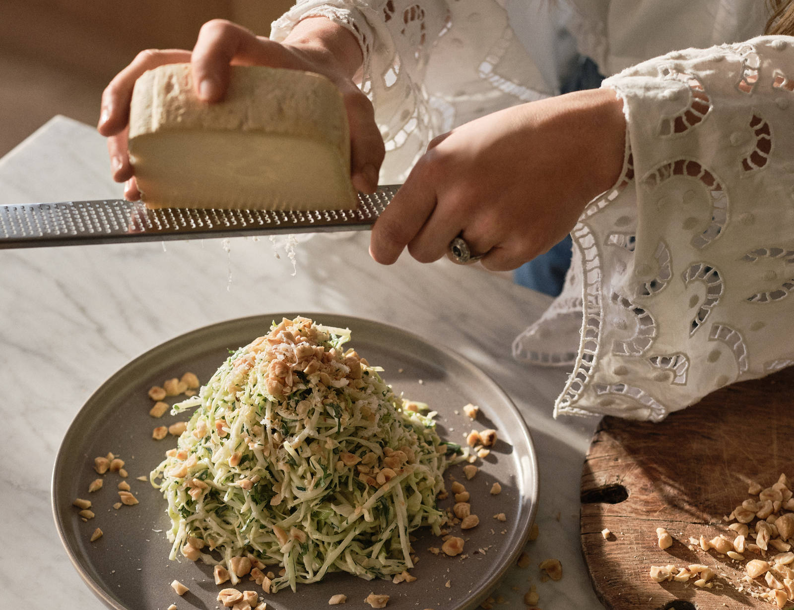 Närbild på Siri Barje som river ost över en tallrik med gurksallad och jordnötter.