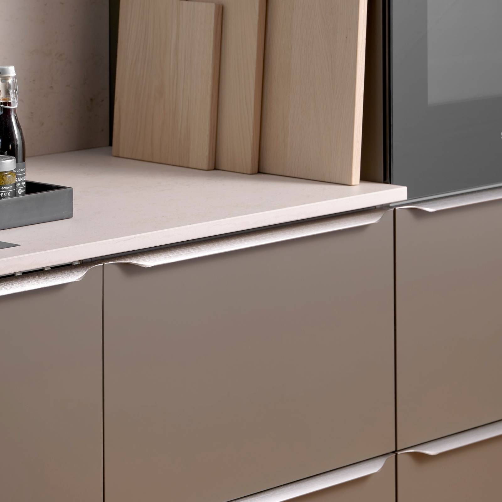 Minimalistisk brun køkken Newline Bark fra INVITA med indbygningsovne i højskabe, diskret greb i stål og lys beige bordplade med matchende splashback