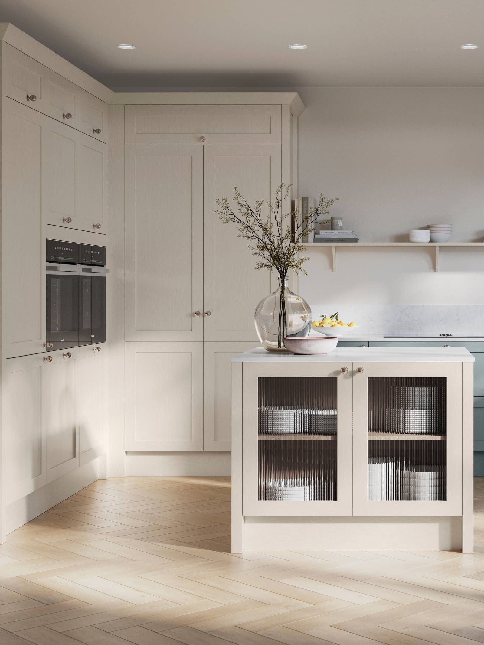 Open floorplan kitchen with small kitchen island in Wardley kitchen from Magnet in the light shade Limestone as well as blue Duck egg, decorated with flowers in glass vases and earth toned ceramics.