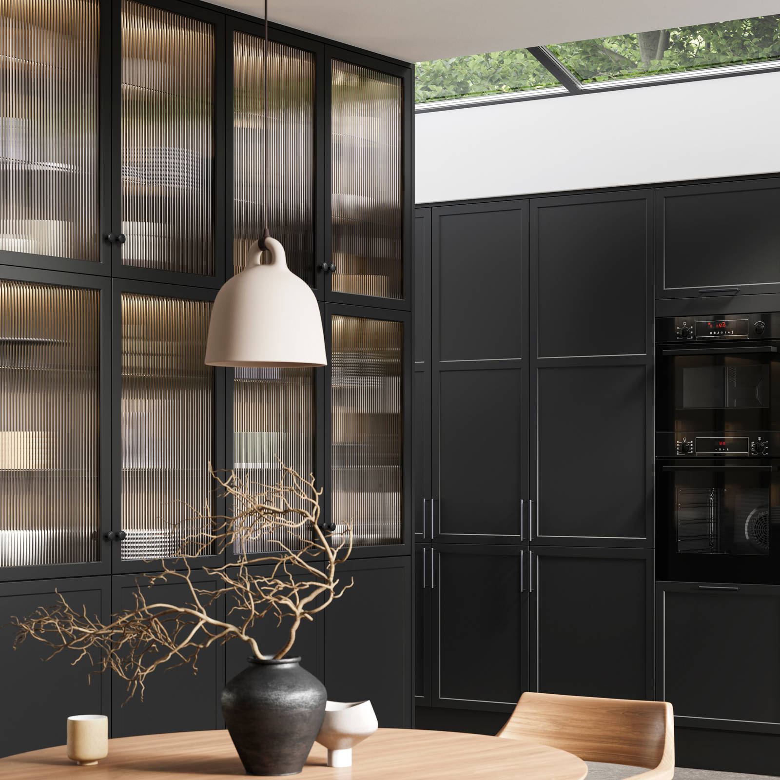 View of modern shaker kitchen Brunswick Sumi Black, with screen extractor over induction hob, tall fluted glass doorsvitrine cabinets, black frame skylights with wood dining table and chairs in foreground.