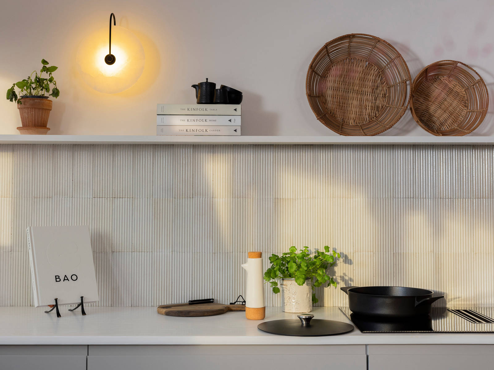 Countertop of Yasmin Wyatts matt finish Luna kitchen from Magnet, splashback and wall shelf, a black skillet pan on the AEG built-in FlexiBridge Hob with Extractor