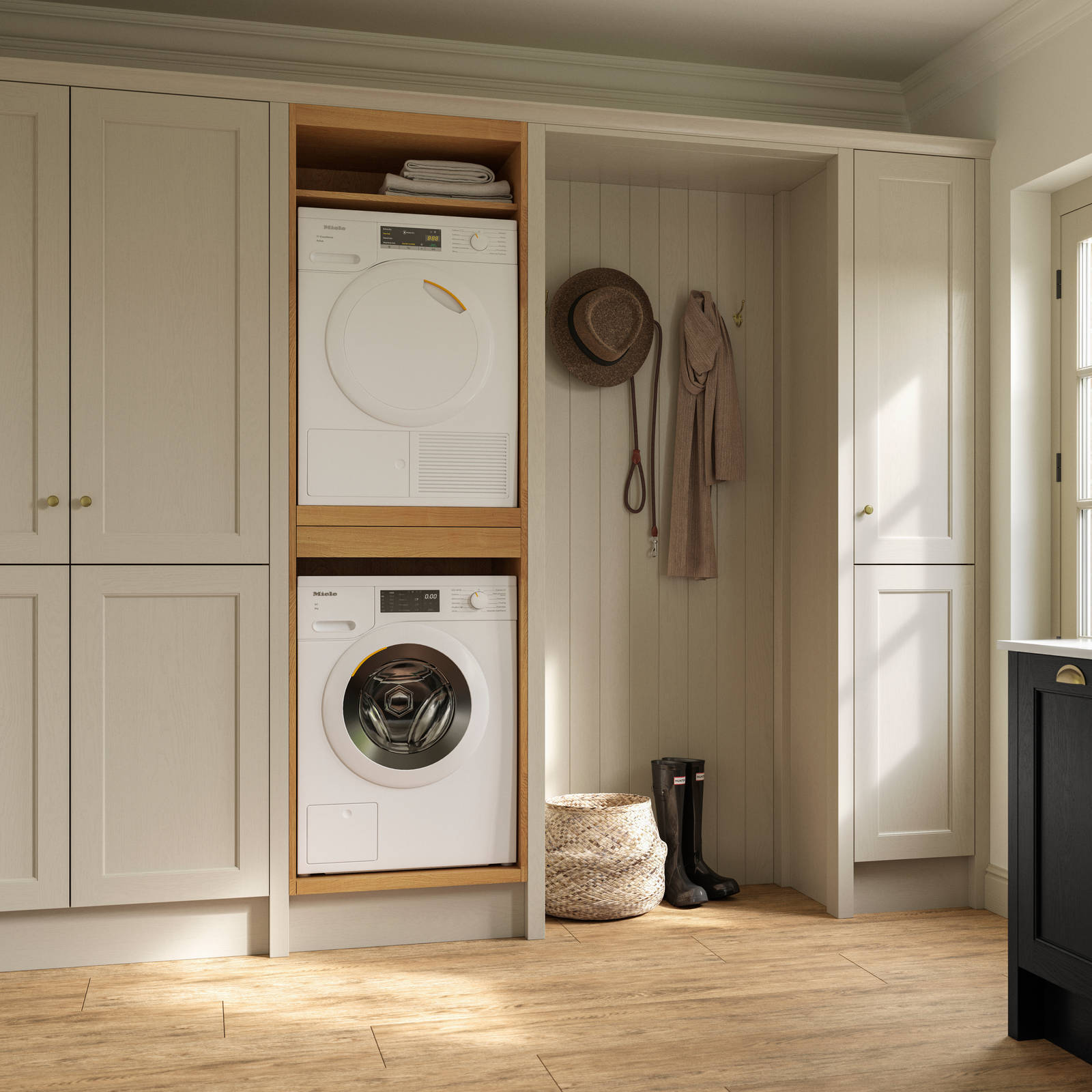 Utility room with Traditional Shaker-style tactile woodgrain Ludlow French Clay cabinets, washing machine and tumble dryer, Ludlow Sumi Black kitchen with brass accessories, Amtico oak stripwood vinyl flooring.