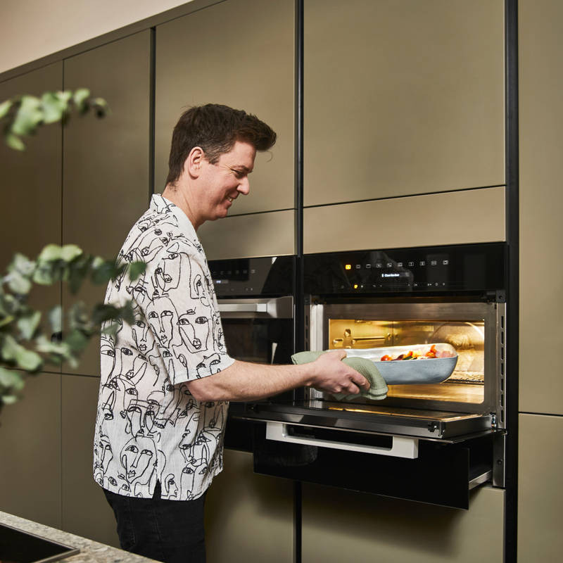 James using oven in the Dramatic neutral Soho Balmoral kitchen from Magnet with modern slab fronts.