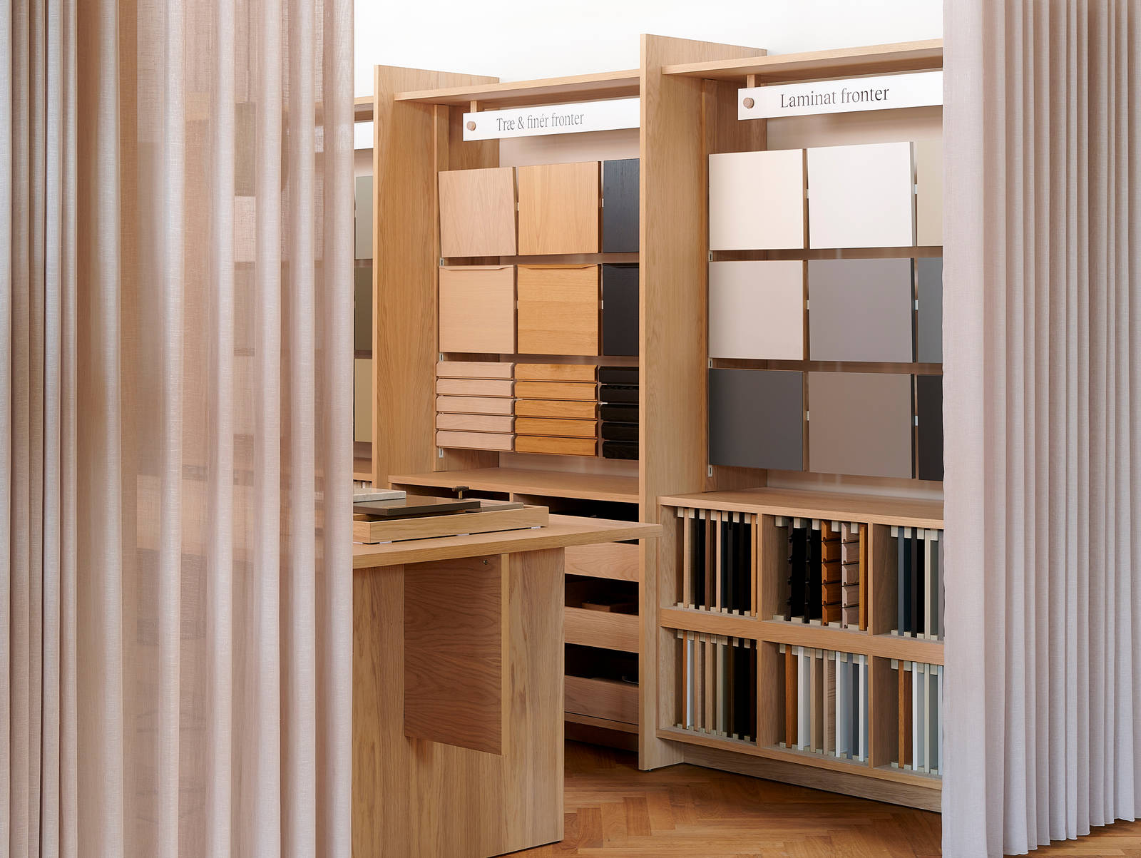 Væghylder med prøver af køkkenlåger i forskellige stilarter og farver i INVITAs butik