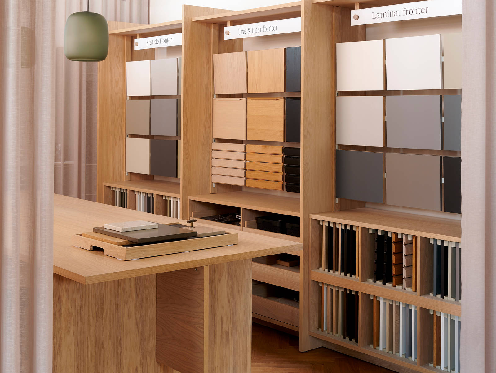 Væghylder med prøver af køkkenlåger i forskellige stilarter og farver i INVITAs butik