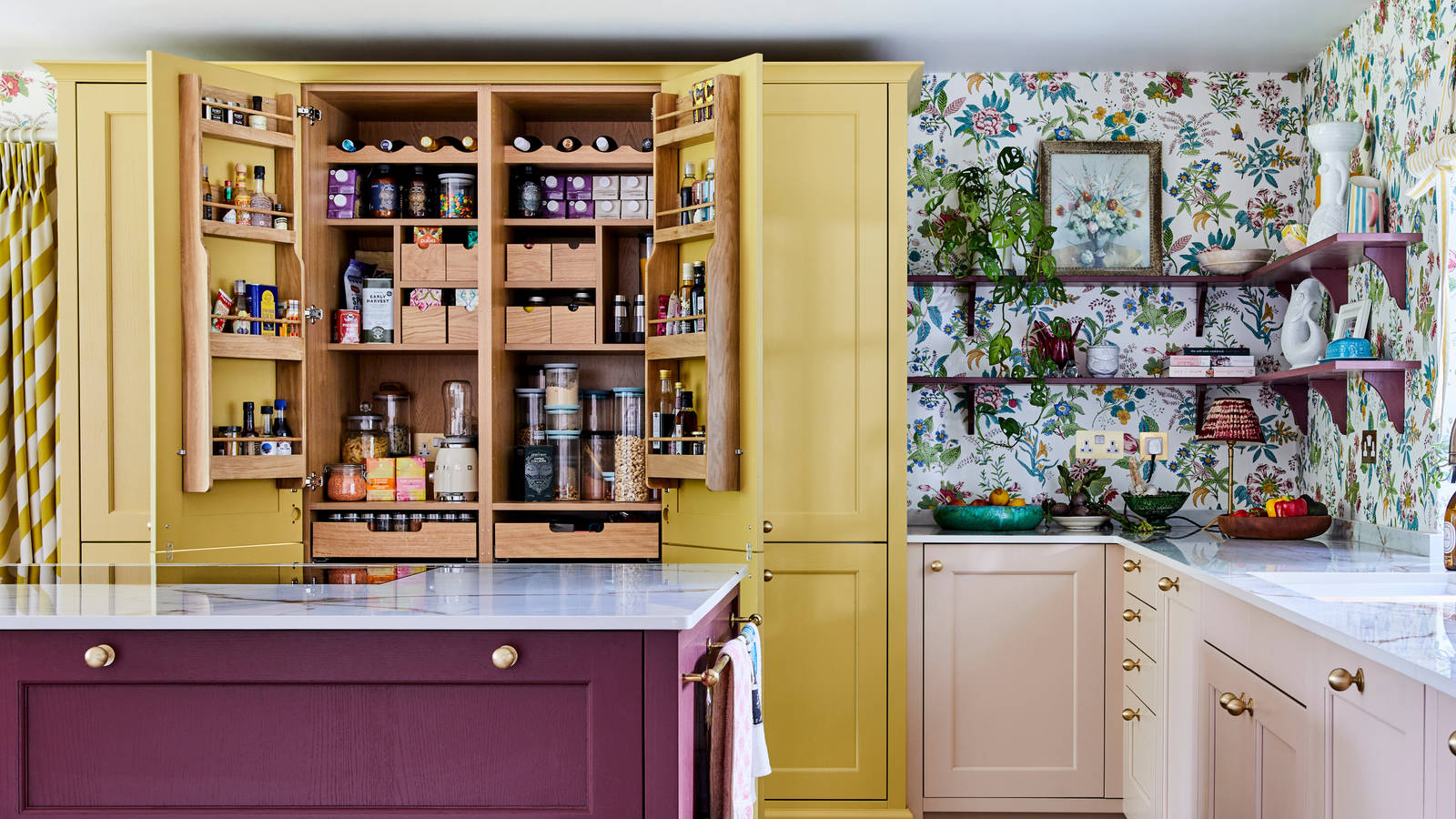 Shaker kitchen with open shelves displaying colourful dishes. Cabinets painted in red, pink, and yellow.