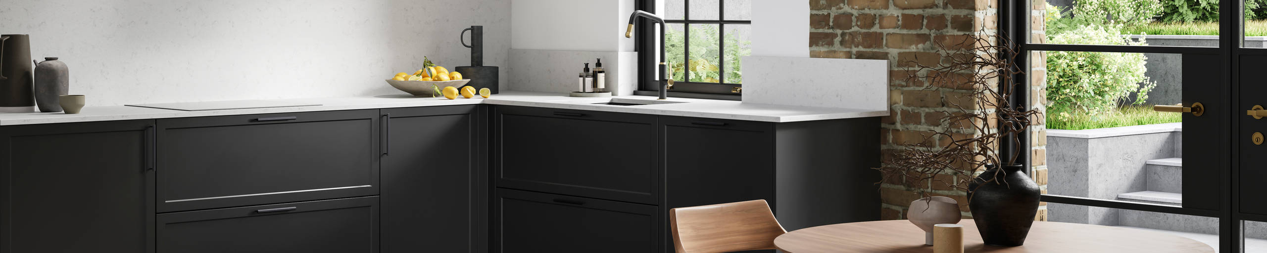 View of modern shaker kitchen Brunswick Sumi Black, with screen extractor over induction hob, black frame skylights with wood dining table and chairs in foreground, combination of white walls and sxposed brick wall.