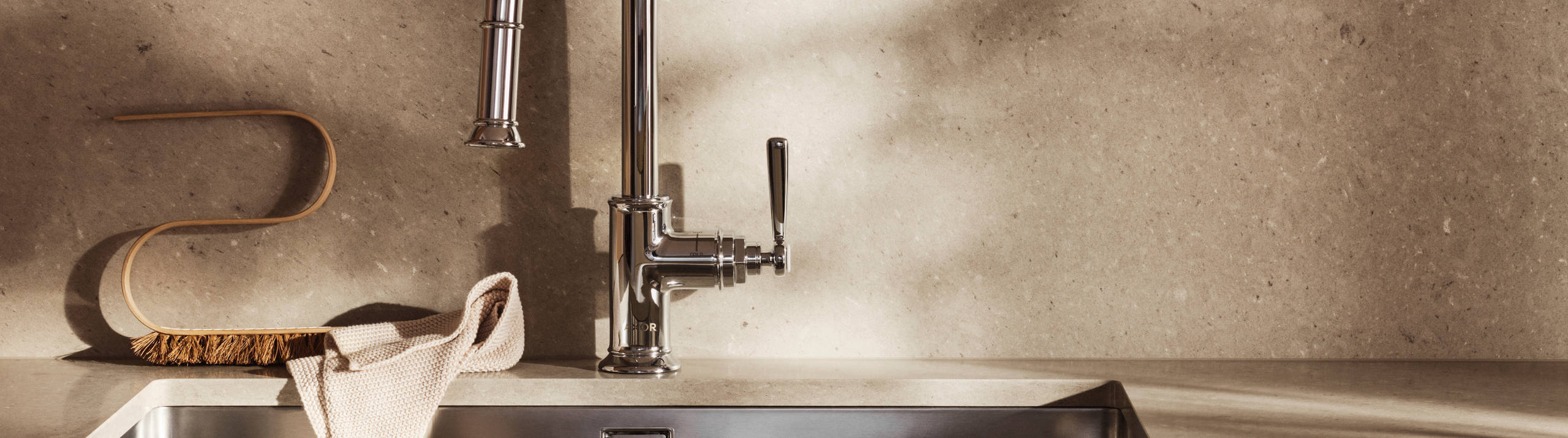 Köksbänk med beige slät kökslucka Arkitekt Plus gryning, bänkskiva, stänkskydd och vägghylla i matchande kompositsten, dekorationer på hyllan, falsk belfast-diskho i matchande dekorativ stenfront.