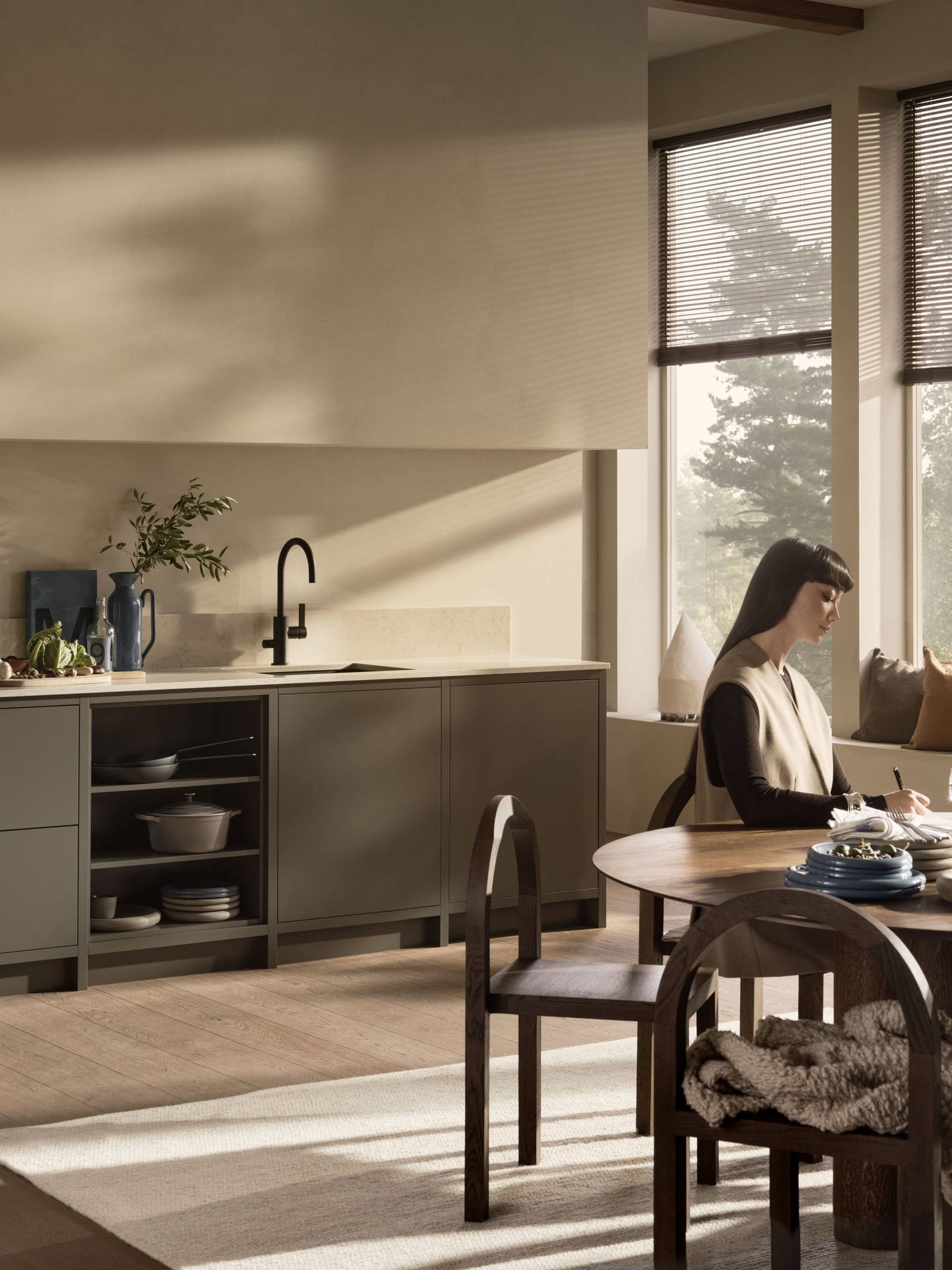 En kvinna sitter vid ett köksbord i ett Warm Minimalism Marbodalkök.