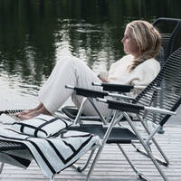 Lotta Agaton i en stol på bryggan vid Piteälven intill landstället