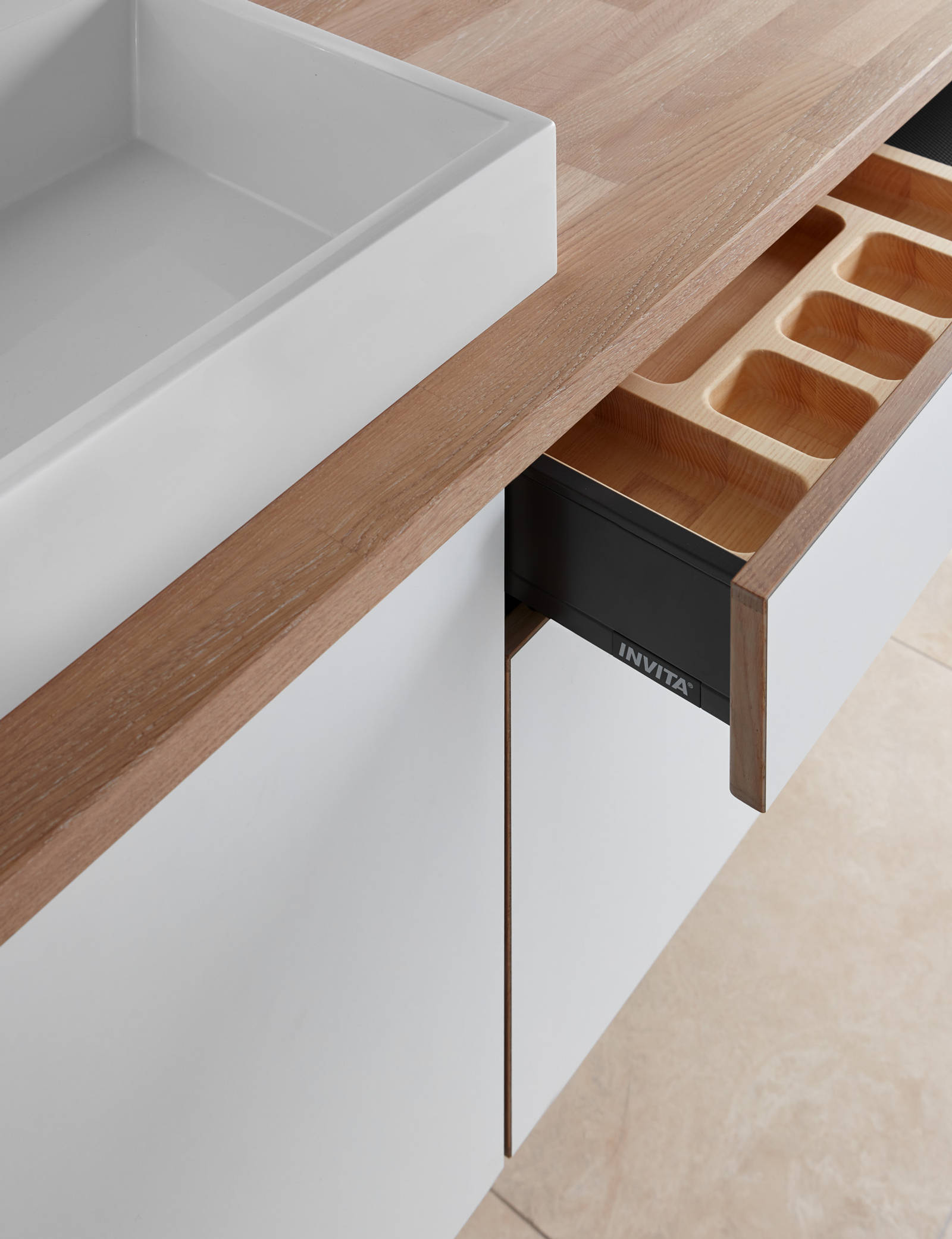Nærbillede av åpen badeværelsesskuffe i badeværelse Comet Frost fra INVITA, med bordplade tre og hvid vask