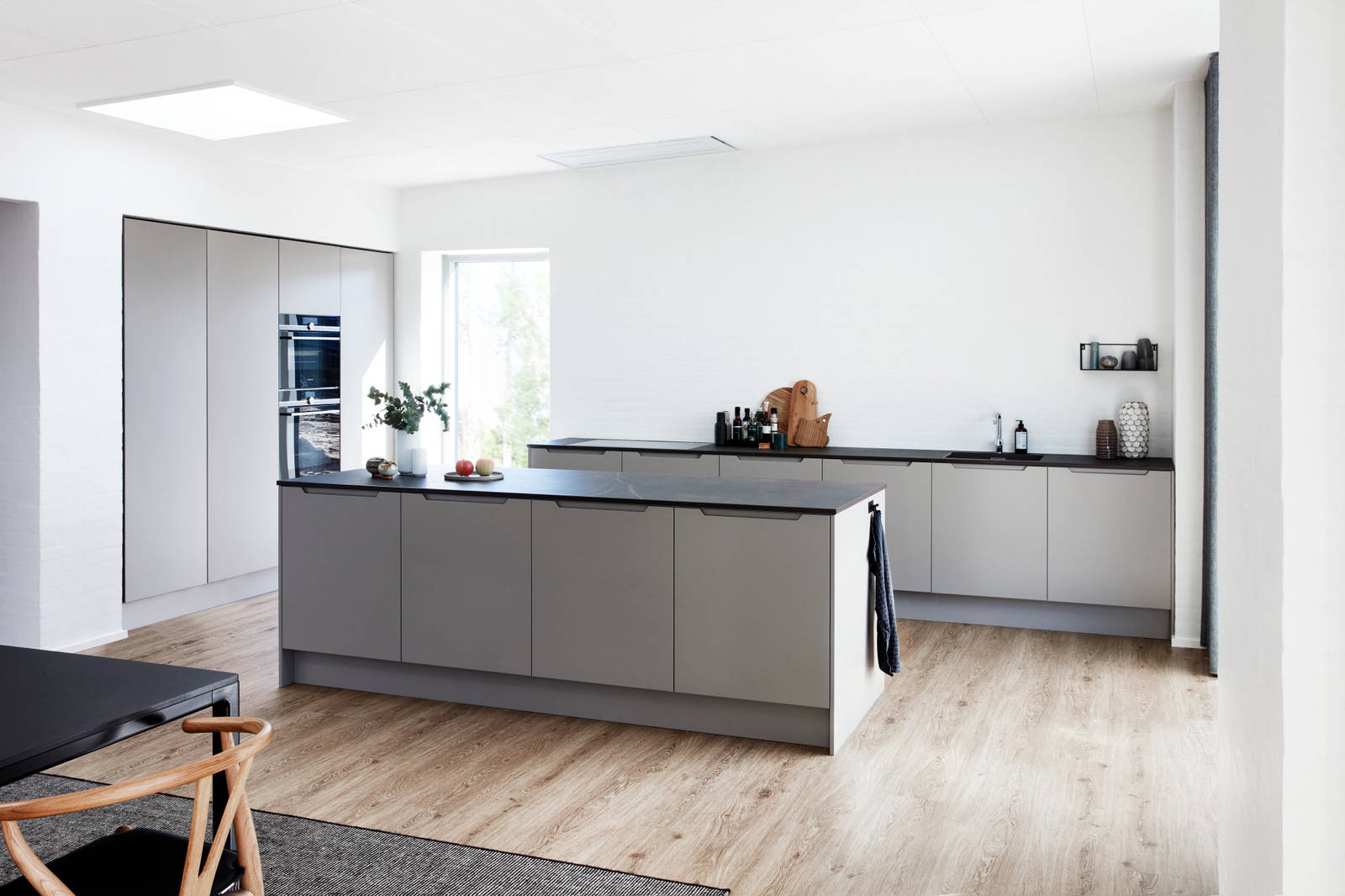 Køkken Urban Søsten med køkkenø fra INVITA med indfræsede greb og sort bordplade