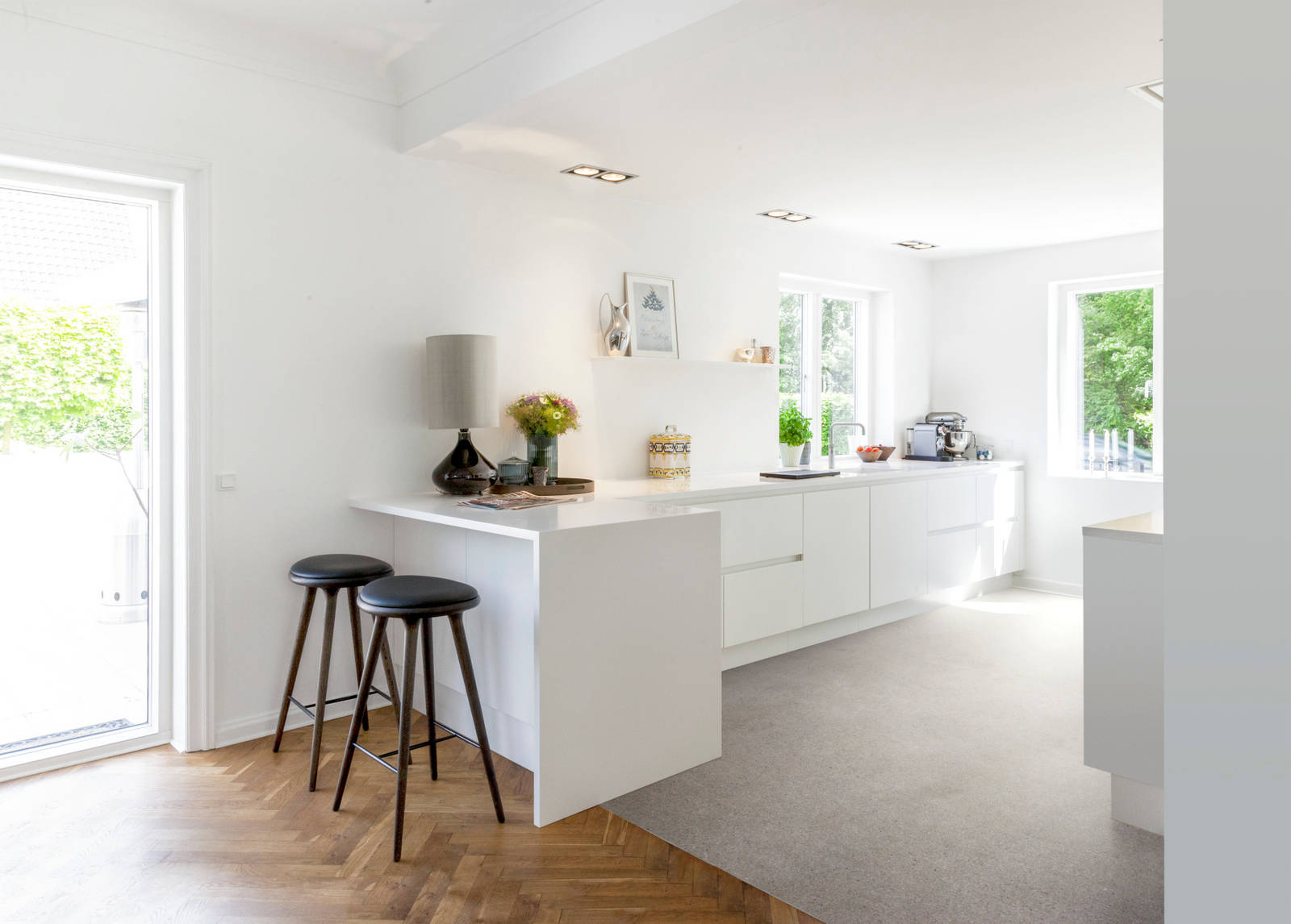 Grebsfrie hvide køkkenet Highline Frost med indfræsede greb i lågerne fra INVITA, hvid bordplade og barstole på halv køkkenø