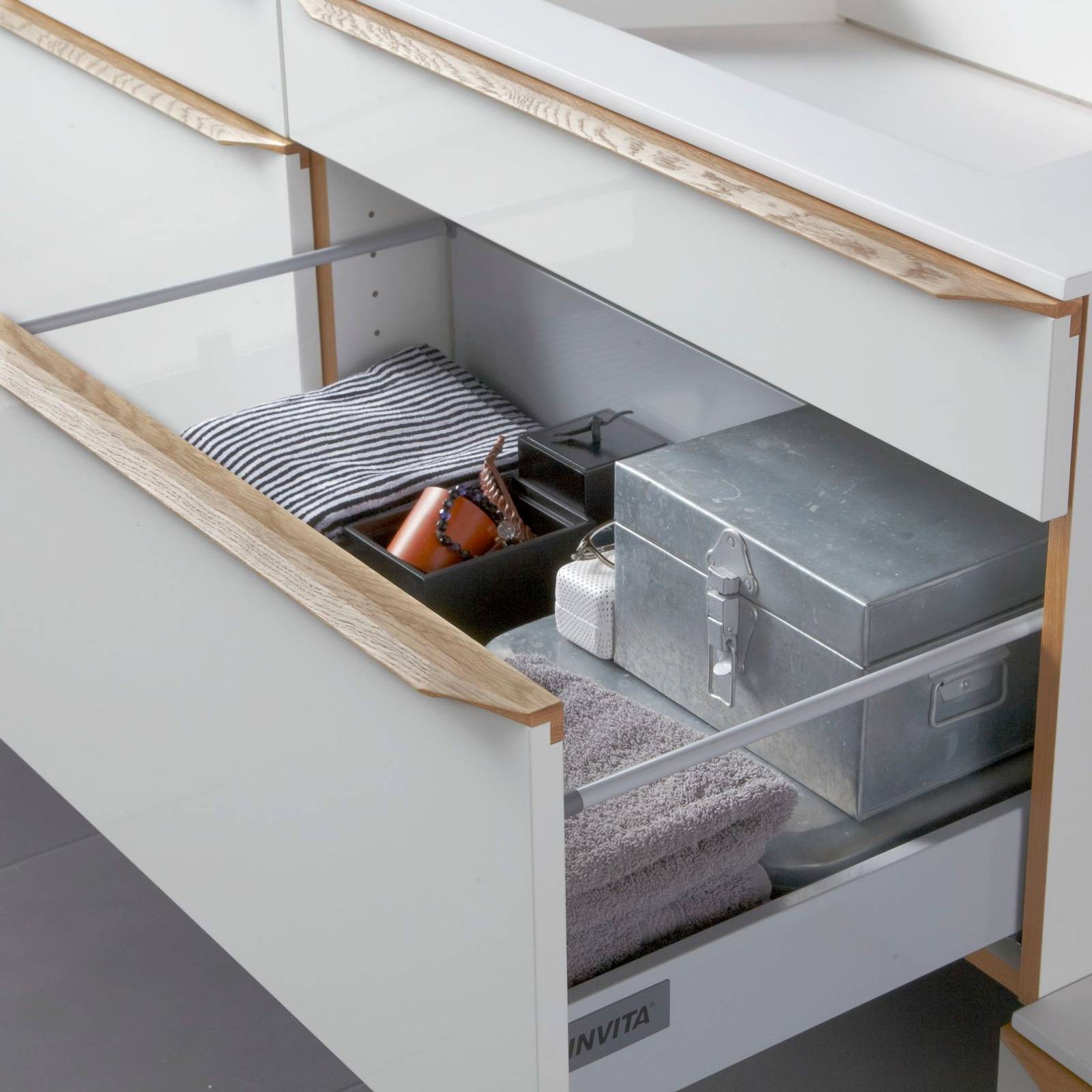 Nærbillede af åben badeværlsesskuffe i luksuriøs grå badeværelsesmøbel Everline fra INVITA med massive trægreb