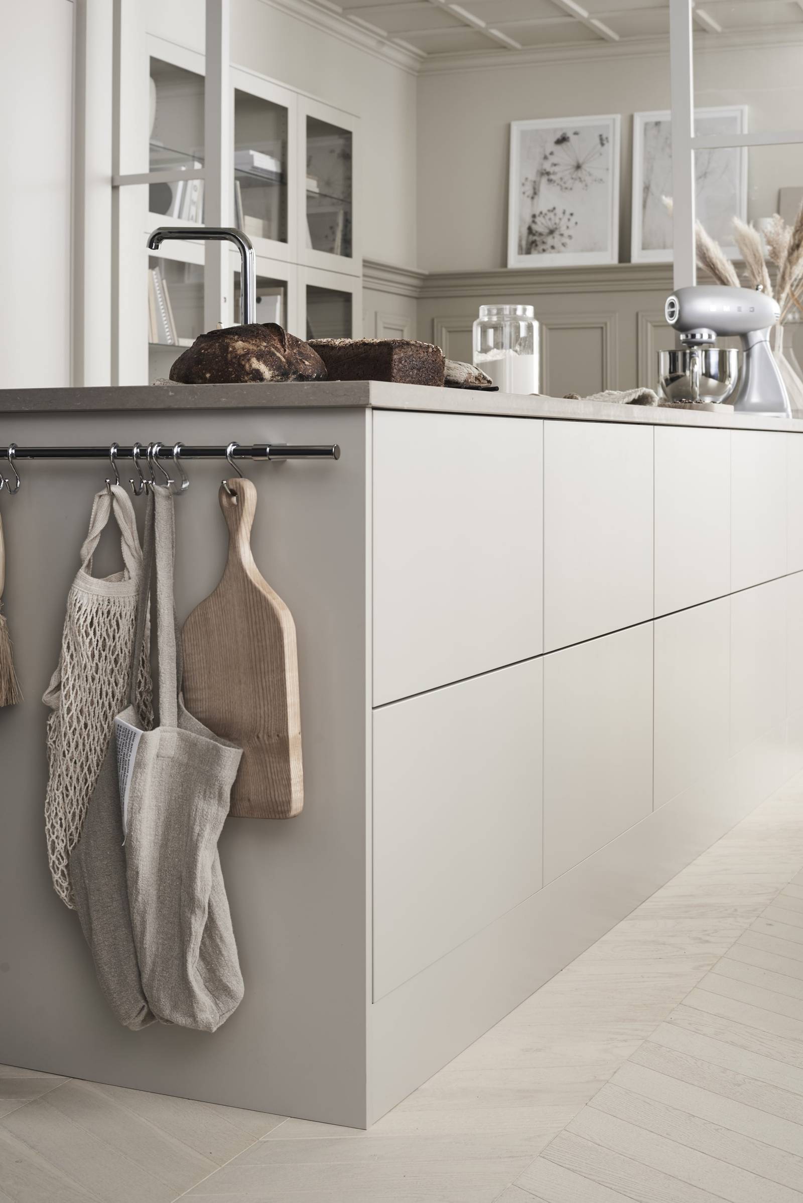 Nærbilde av kjøkkenøya i Sigdals stilige kjøkkenmodell Line Korn, der nybakt brød står på benken og bakemaskinen står klar.