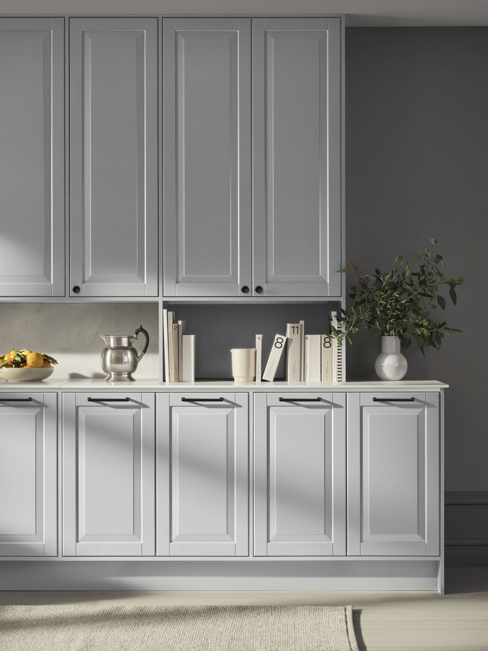 Lys grå landkøkken Nordic Sky fra INVITA med fyldningslåger, sort håndtag, vitrineskab med sprosselåger og hvid marmor laminatbordplade