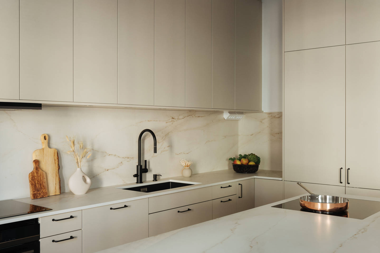 Spishäll i köksö, matt svart blandare och diskho i Filip Poons kök från Marbodal, Arkitekt Plus Sand med svarta handtag och Dekton bänkskiva samt stänkskydd