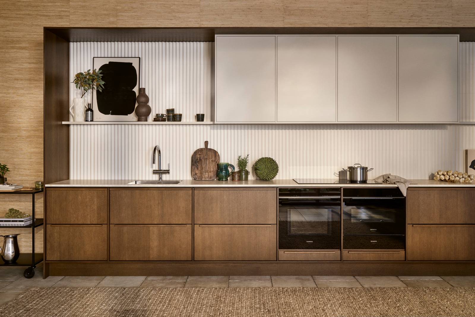 Mørk eg køkkenbænk Forever Oak fra INVITA kombineret med overskaber Athena Sand, hvide fliser, bordplade og massiv ek håndtag, ovn og dampovn fra Siemens