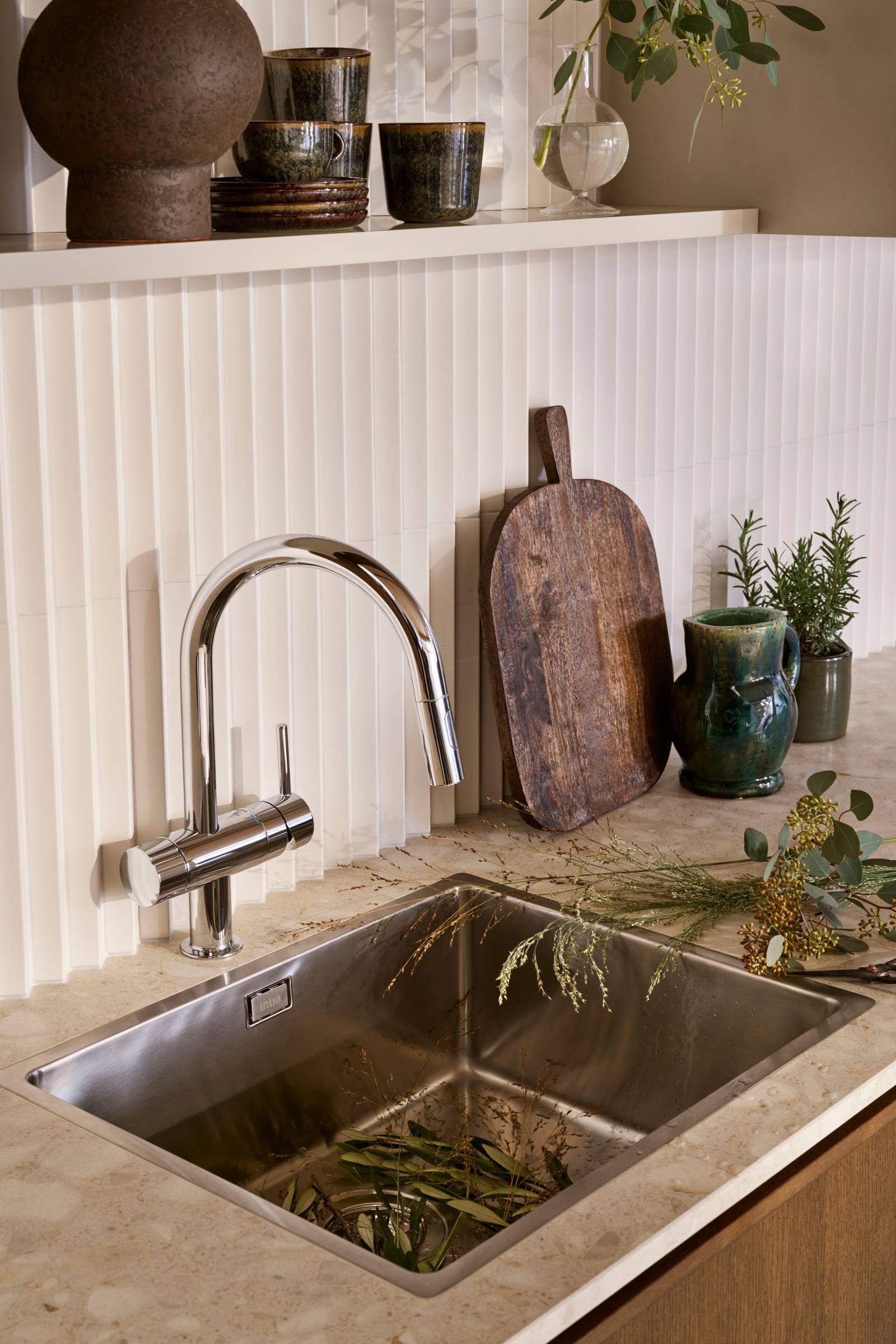 Nærbillede av rustfrit stål vask og armatur i mørk eg køkkenet Forever Oak fra INVITA med hvid fliser backsplash