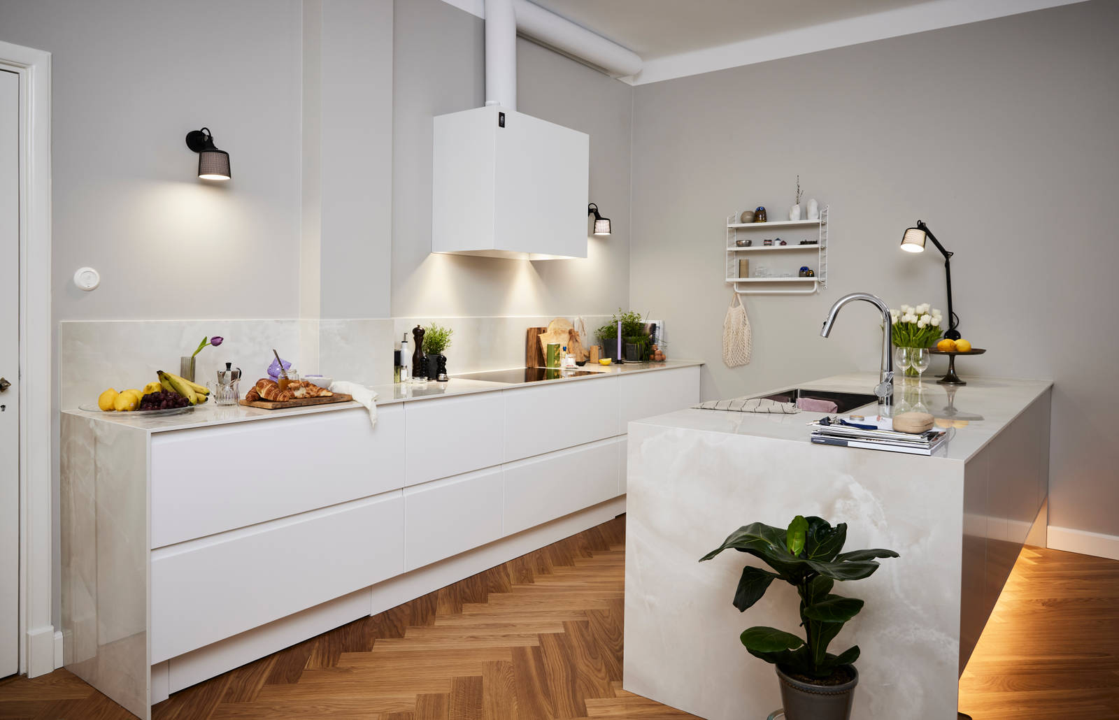 Valkoinen keittiö ja harmaa keittiösaareke, jossa sisäänrakennettu kahvaura ovessa, Dekton Helena kivitaso ja yhteensopiva roiskepala, puinen kalanruoto