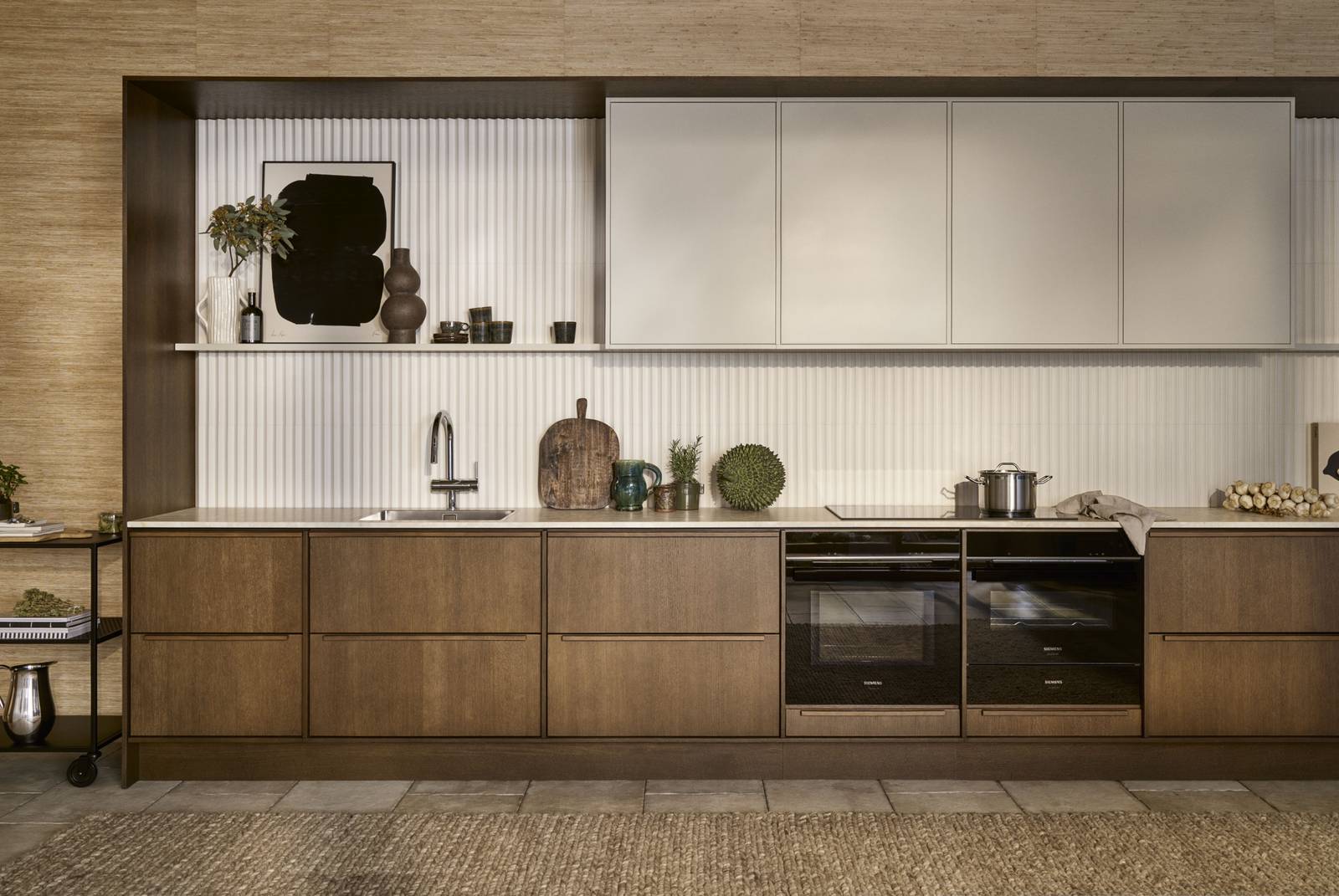 Mørk eg køkkenbænk Forever Oak fra INVITA kombineret med overskaber Athena Sand, hvide fliser, bordplade og massiv ek håndtag, ovn og dampovn fra Siemens