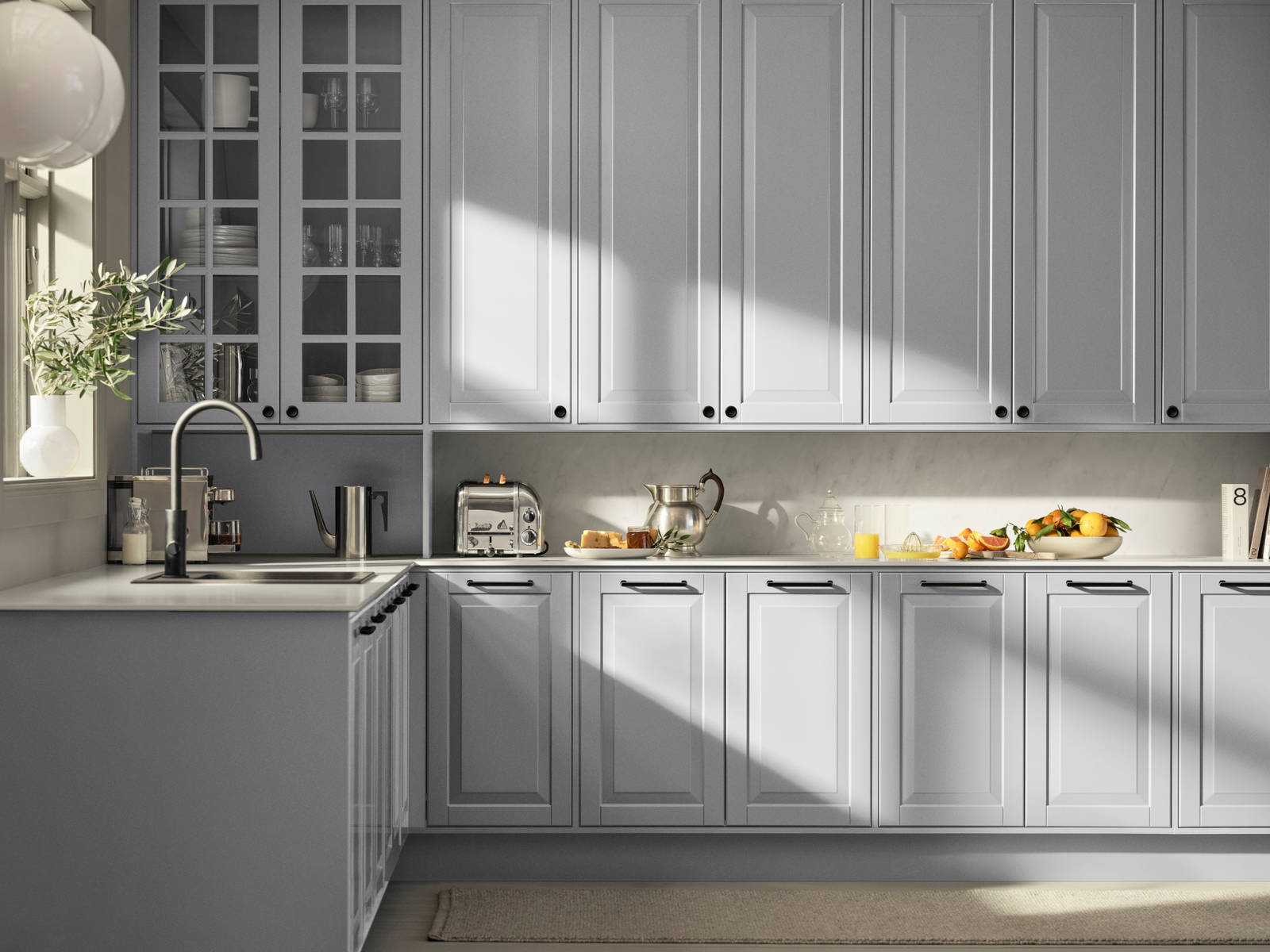 Lys grå landkøkken Nordic Sky fra INVITA med fyldningslåger, sort håndtag, vitrineskab med sprosselåger og hvid marmor laminatbordplade