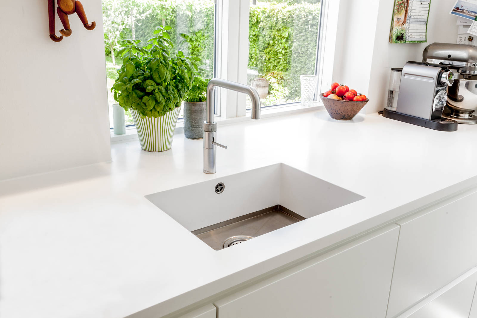 Grebsfrie hvide køkkenet Highline Frost med indfræsede greb i lågerne fra INVITA, hvid bordplade og armatur i rustfrit stål