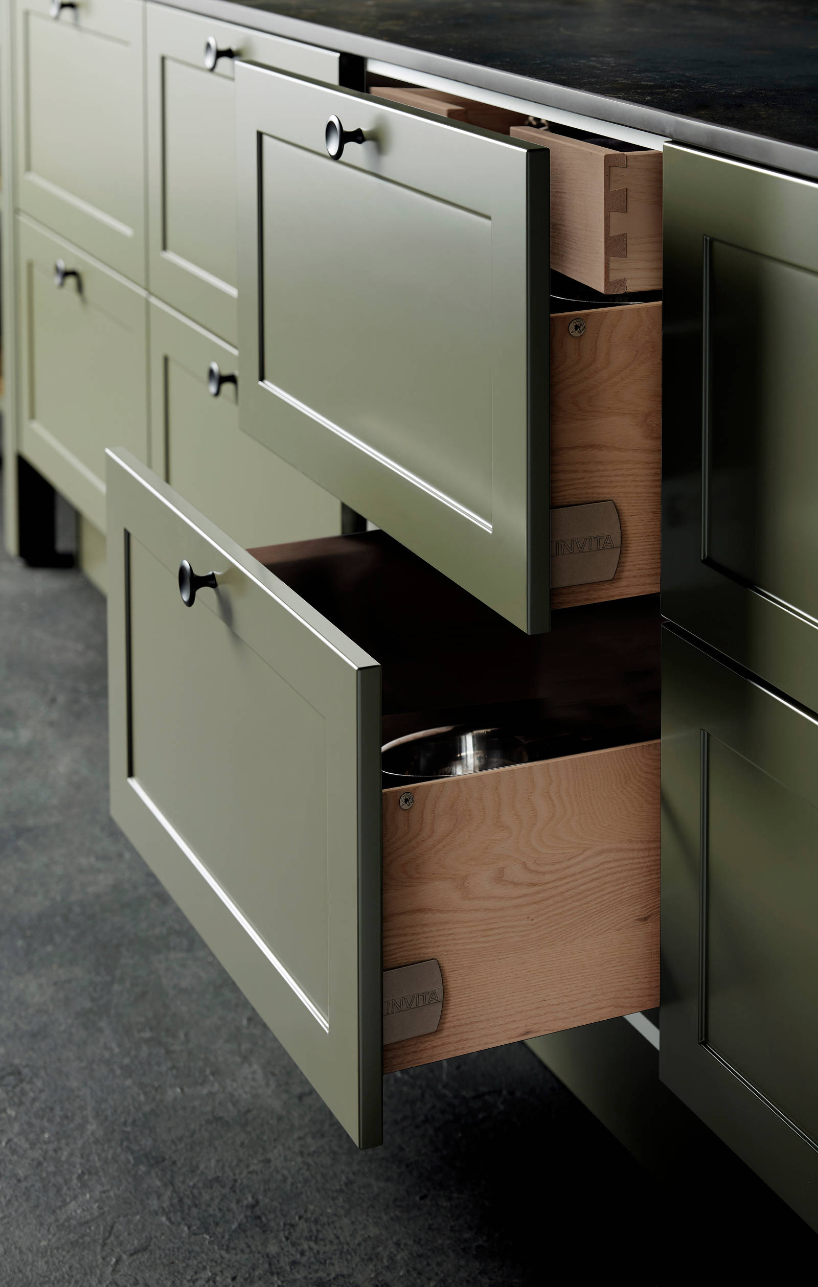 Nærbillede av åben køkkenskuffe i Nostalgisk grønn køkken Northern Shaker Olivenfra INVITA med håndtappede træskuffer og moderne linjer på fyldningslågerne