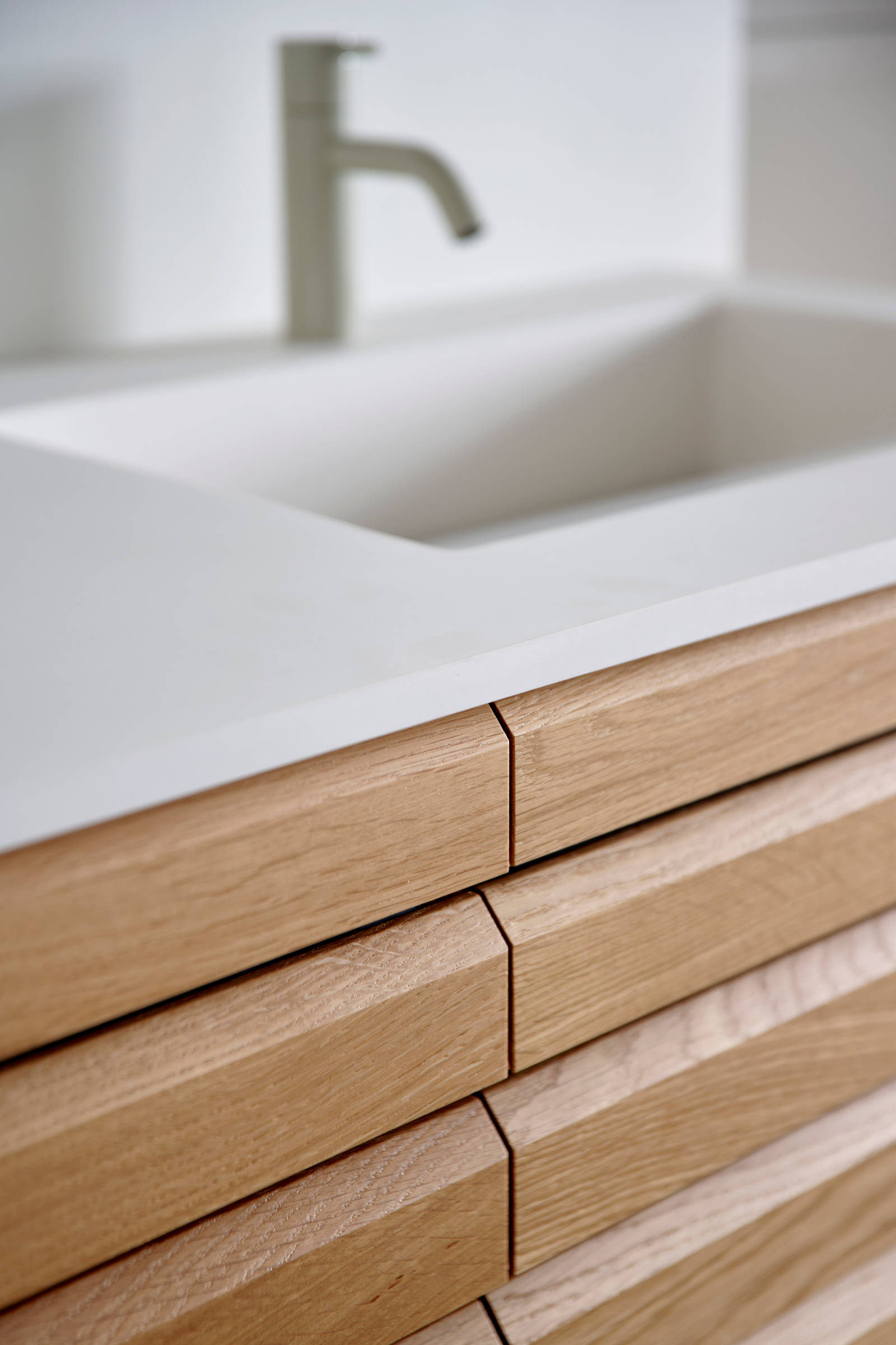 Nærbillede af snedkerbadeværelse Ikon Finér eg natur fra INVITA med håndplukkede, massive egetræslameller med hvid vask