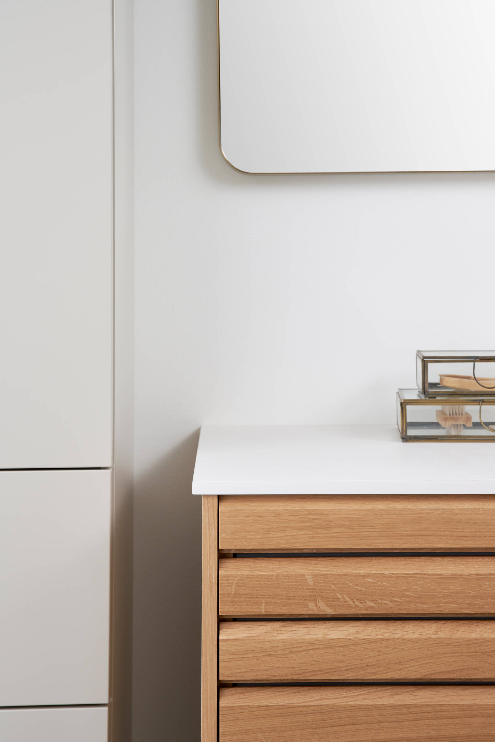 Nærbillede af hjørne i snedkerbadeværelse Ikon Finér eg natur fra INVITA med håndplukkede, massive egetræslameller med hvid vask