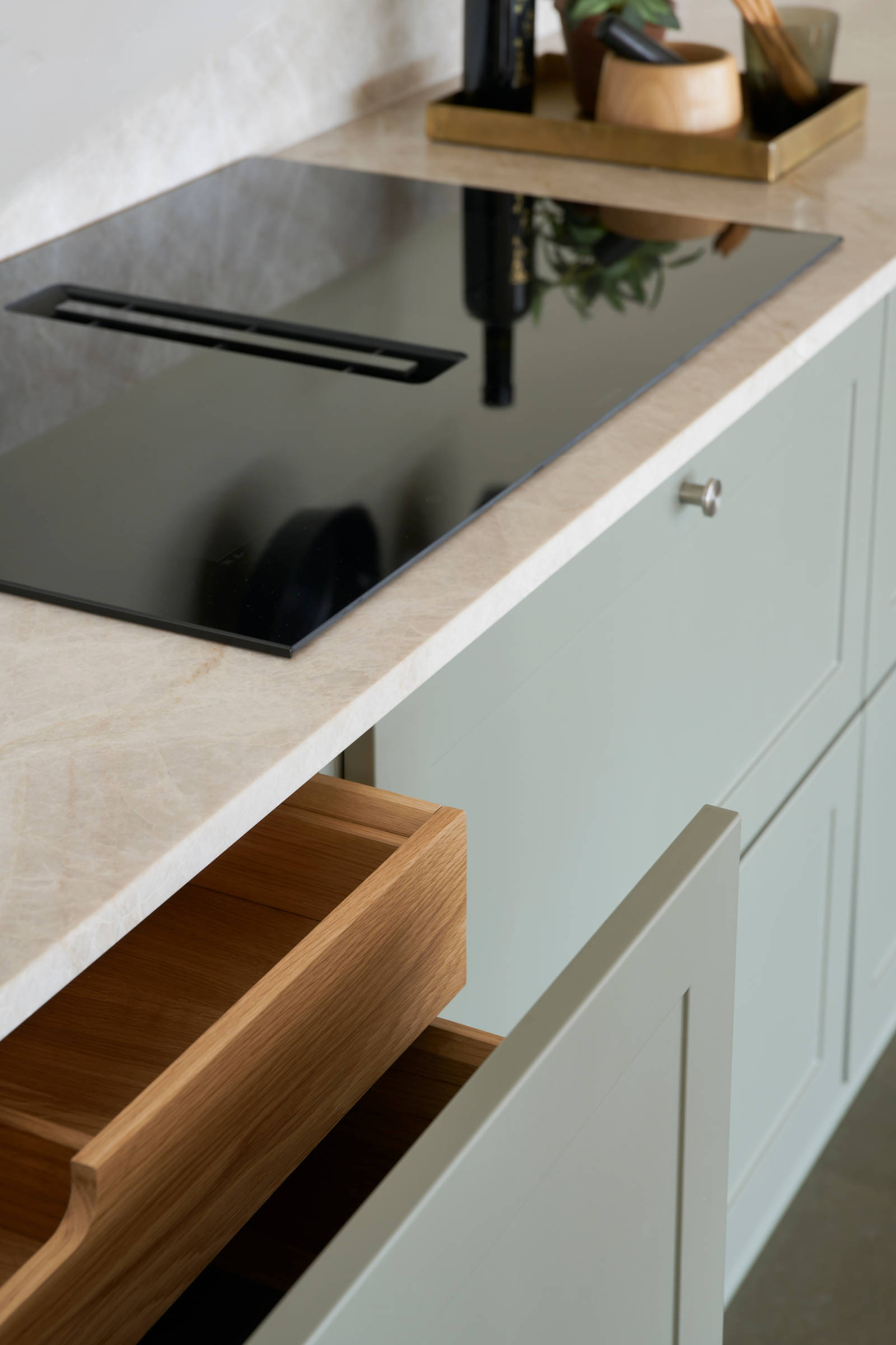 Nærbillede af induktionskomfur Grønn retrokøkken Square Salvie køkken fra INVITA med rustfri stål håndtag, armatur og vask med grå marmor bordplade