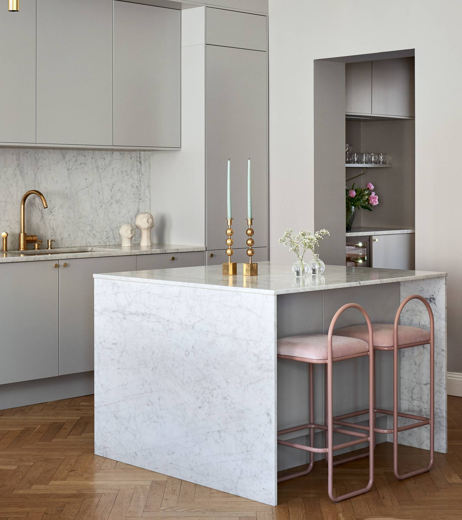 Lys grå Athena Sky køkken fra INVITA, køkkenø med dekorativ side og bordplade i lys grå marmor, håndtag, vandhane og lysestager i messing