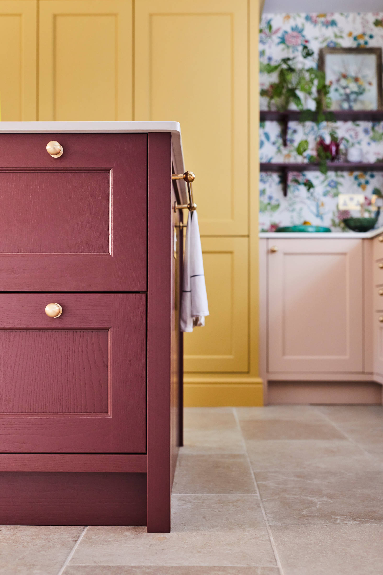 Close-up of corner of Ludlow Burlington Red kitchen island, with its tactile woodgrain, with brass handles and a towel hanging on brass bar on the edge.