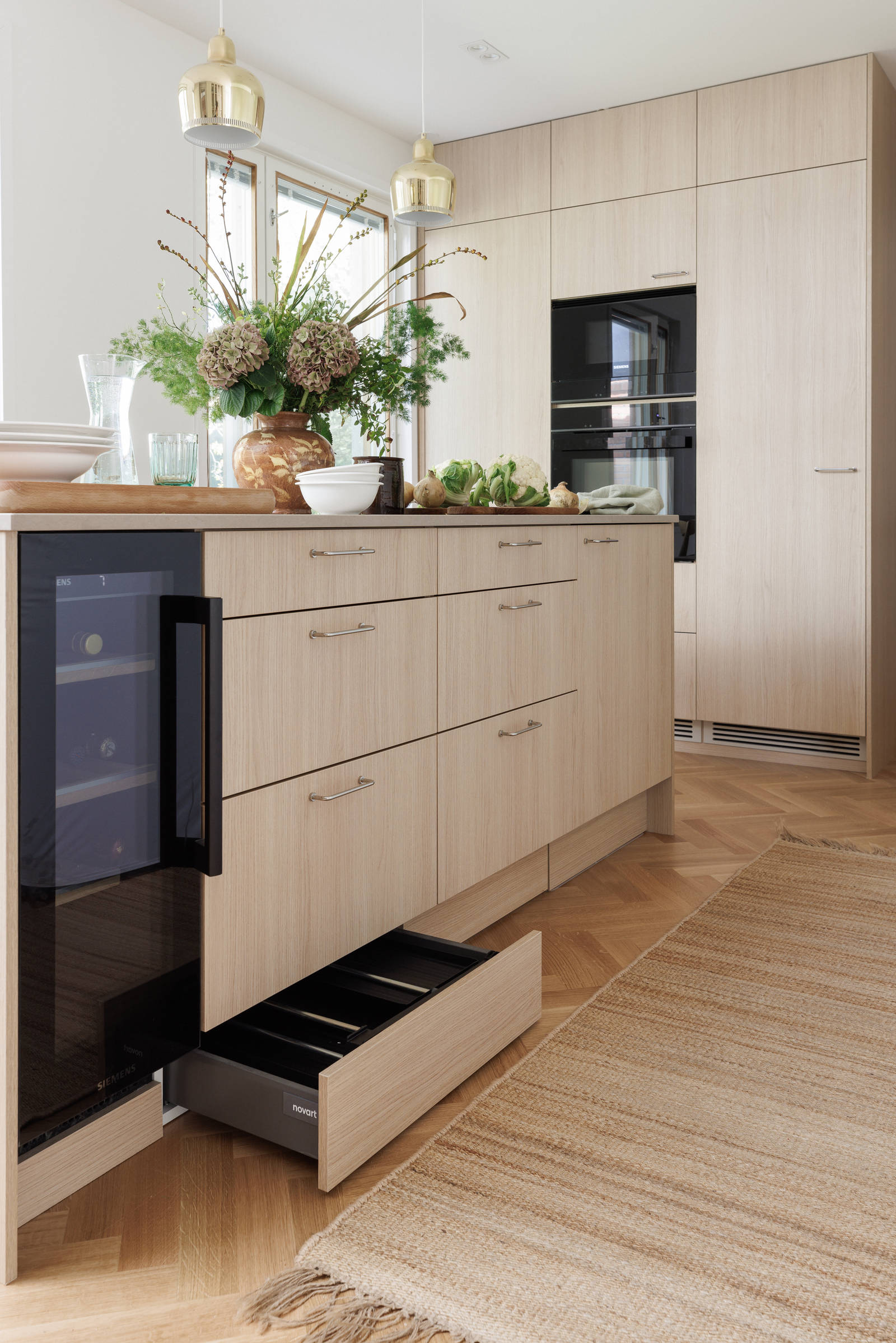 Aitoa luonnontammea Novartilta, yhdistelmä yhteensopivia puisia ja painonappikahvoja, keittiösaareke hanalla, tiskiallas ja ruostumattomasta teräksestä valmistettu työtaso.