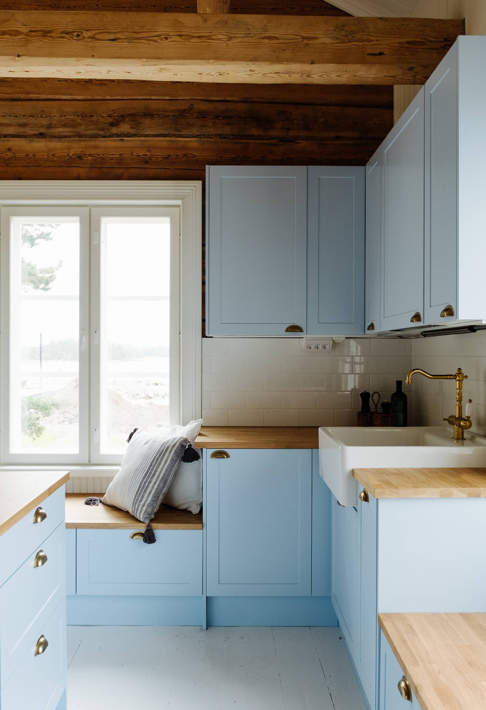 Keittiö, jossa karmiovet erikoissävyssä NCS S 1020-R90B 1800-luvun hirsitalossa, tammitasot, posliinitiskiallas ja messinkihana.