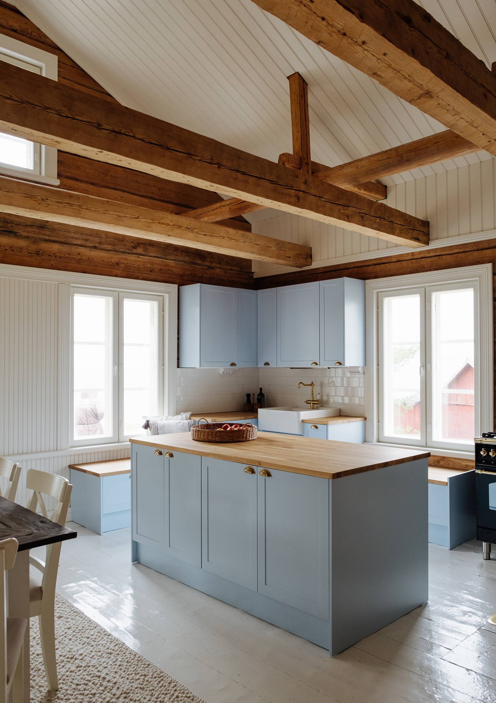 Keittiössä keittiösaareke, karmiovet erikoissävyssä NCS S 1020-R90B 1800-luvun hirsitalossa, tammitasot, posliinitiskiallas ja messinkihana.