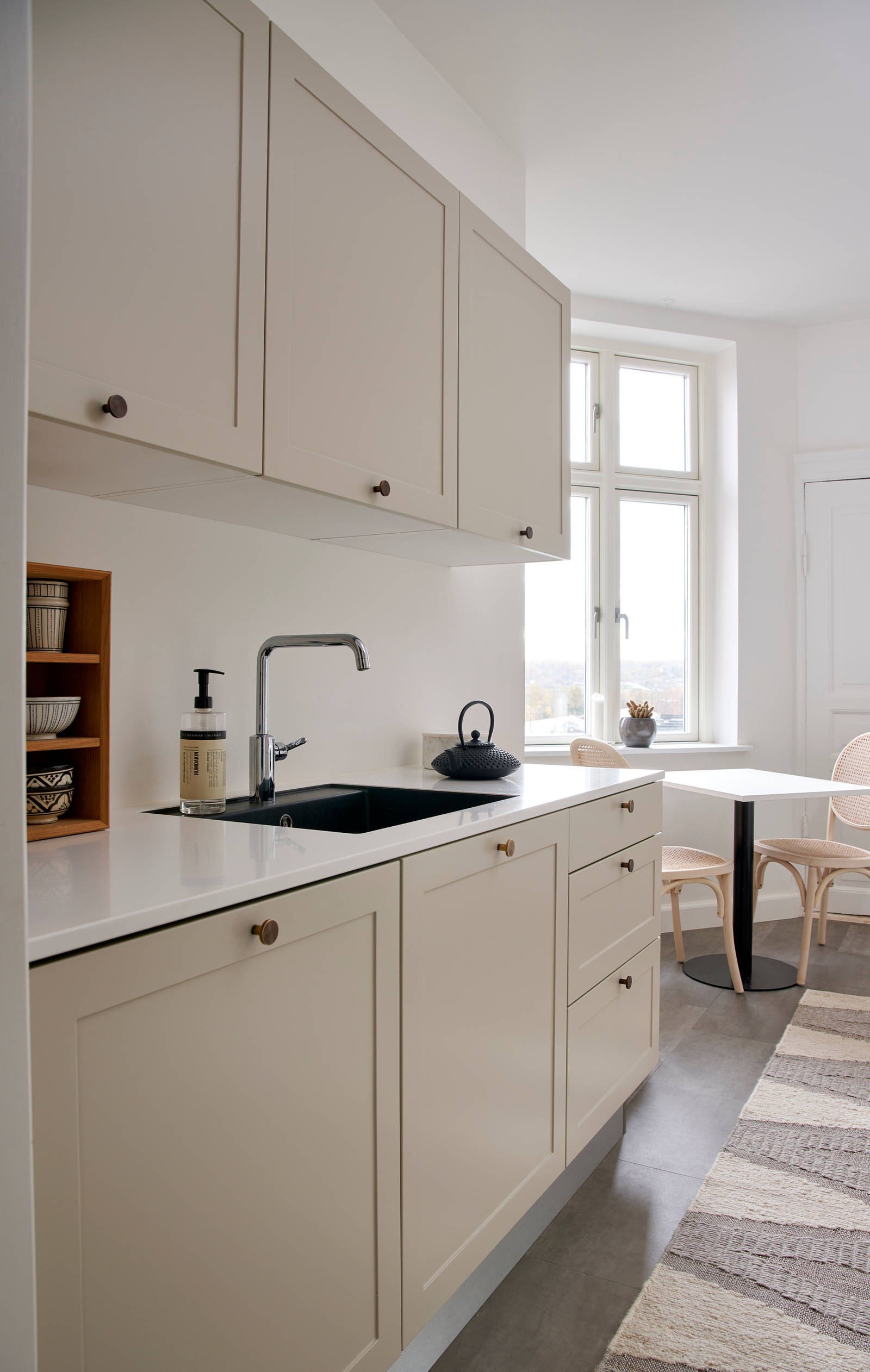 Beige retrokøkken Square Sand køkken fra INVITA med messing håndtag, hvid bordplade